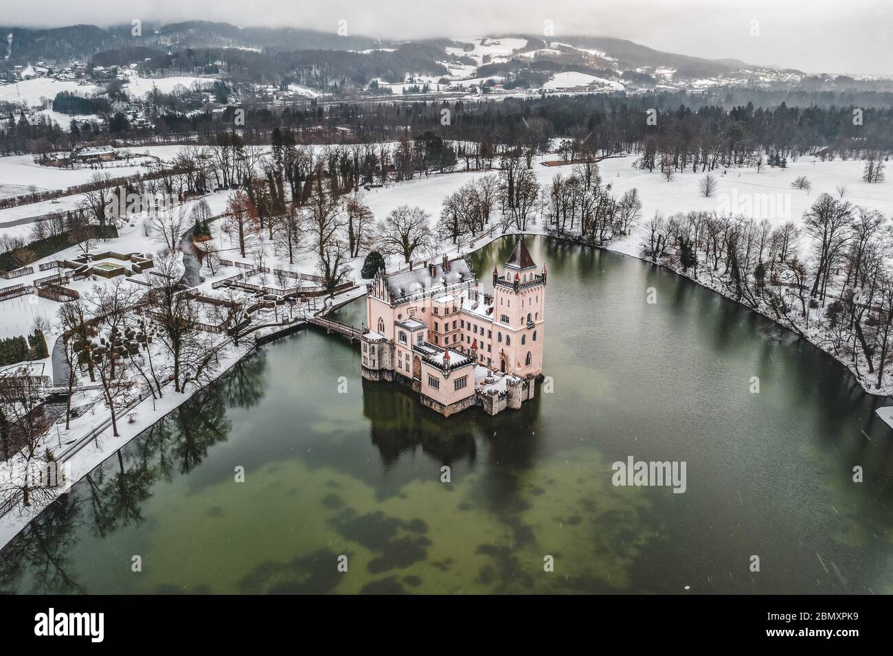 Aerial drone shot of Anif Schloss moated castle in artificial pond at Salzburg outskirts in heavy snow during winter time Stock Photo