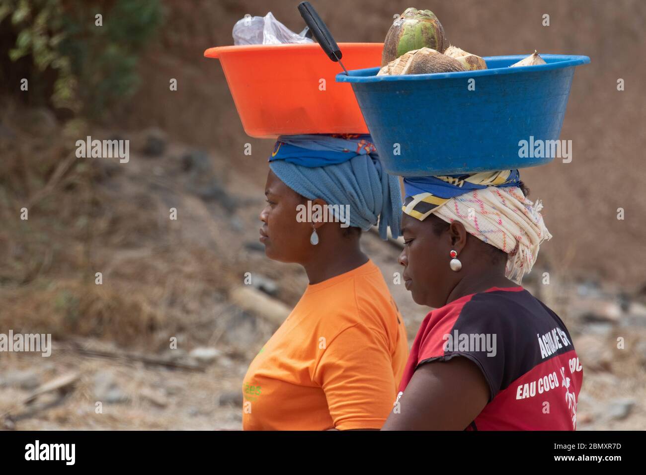 Two local Cape Verdean women transporting food on their heads on the beach near Tarrafa on the island Santiago, Cape Verde / Cabo Verde Stock Photo