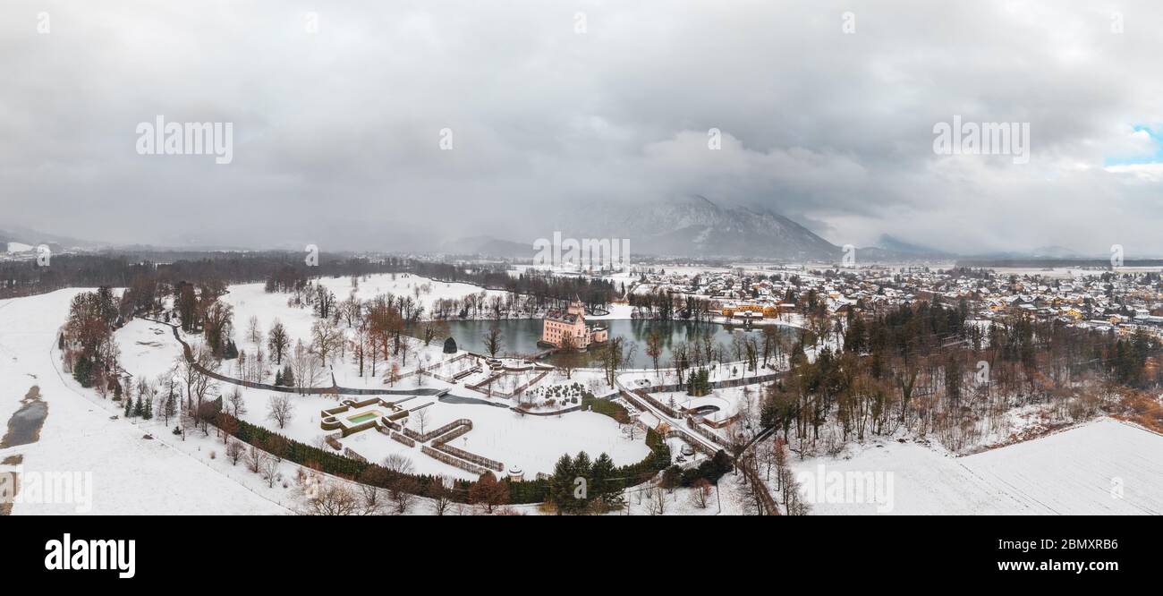 Panoramic aerial view of Schloss Anif castle moated in artificial pond near Salzburg outskirts in heavy snow during winter with view of untersberg  Stock Photo