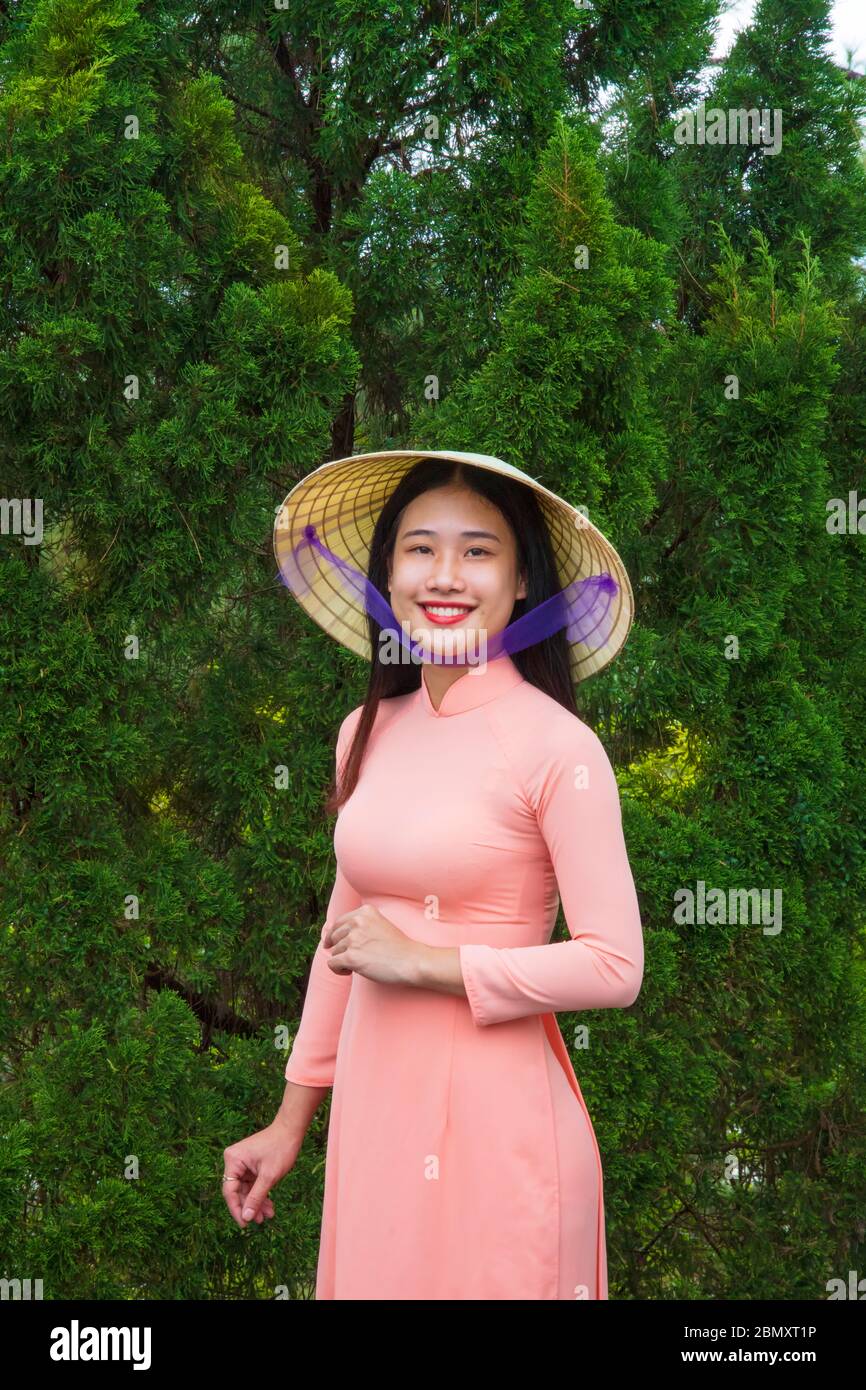 An Vietnamese woman in an Ao Dai dress in the doorway to a temple Stock Photo