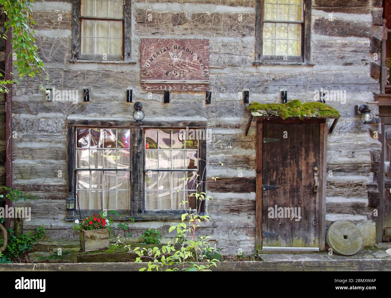old log building, sign, 'Regimental Headquarters G3 Tennessee Volunteer Infantry USA', antique, moss on door overhang, Tennessee; USA, Cumberland Gap Stock Photo