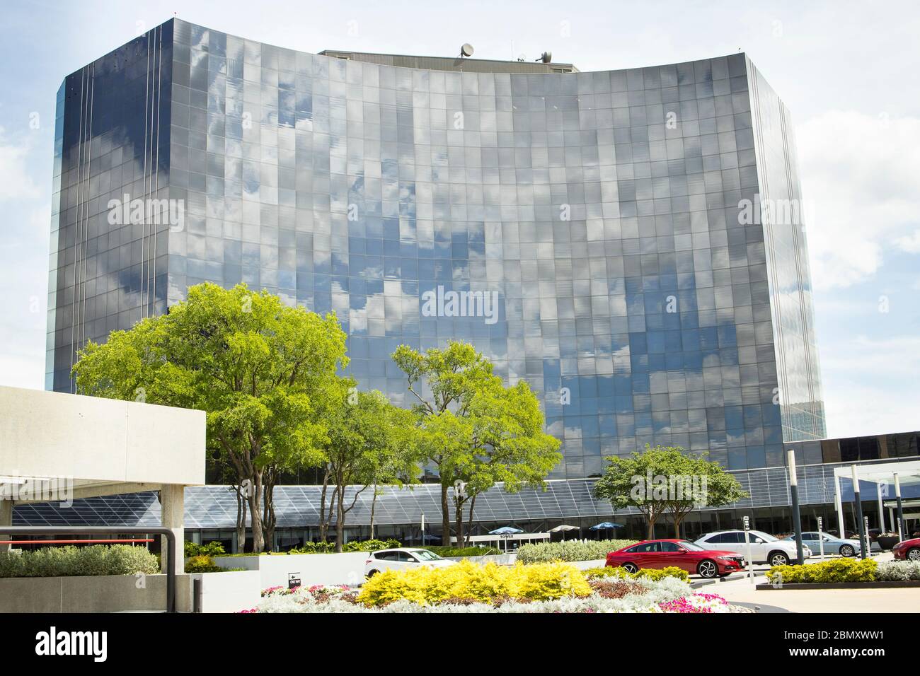Curved front facade and parking lot with flowers show off this modern mirrored office building in Dallas, Texas Stock Photo