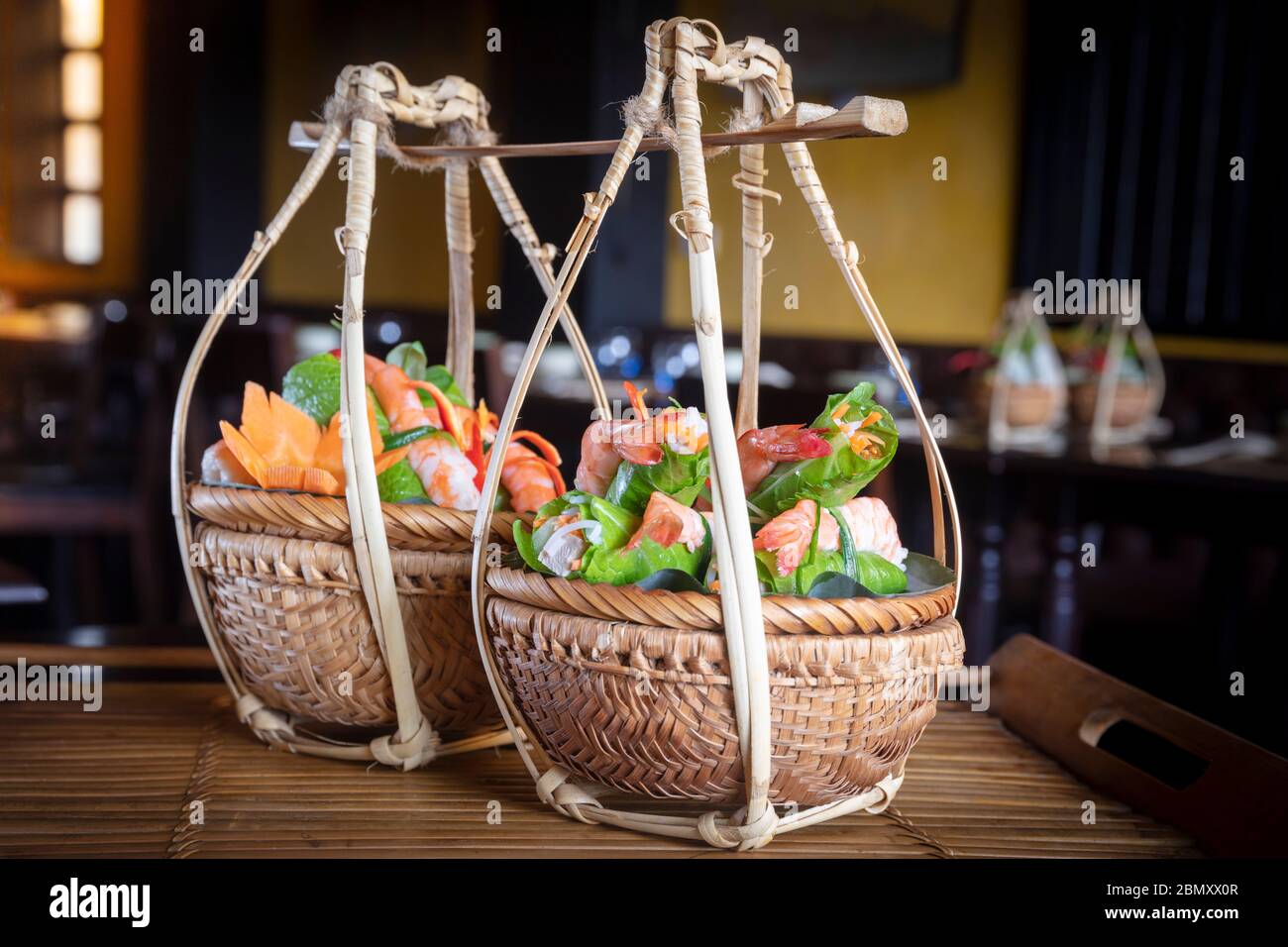 Vietnamese food served in traditional wicker baskets in a restaurant in Hoi An Stock Photo