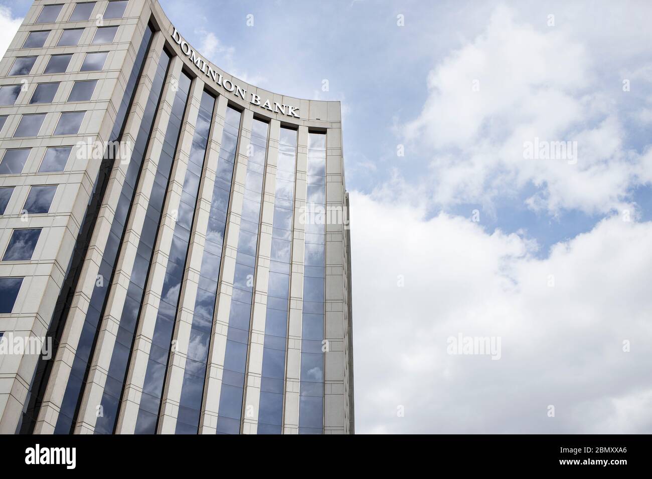 Dallas, Texas bank tower standing against the sky reflecting clouds for an imposing view of business and finance Stock Photo