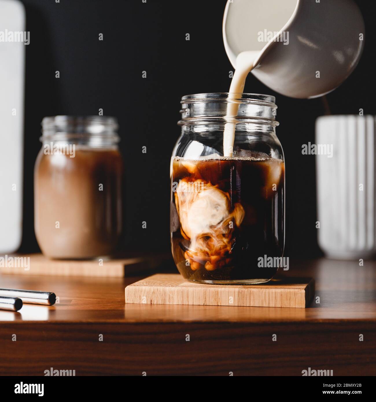 Making iced latte. Pouring vegetarian soy milk into a glass jar with