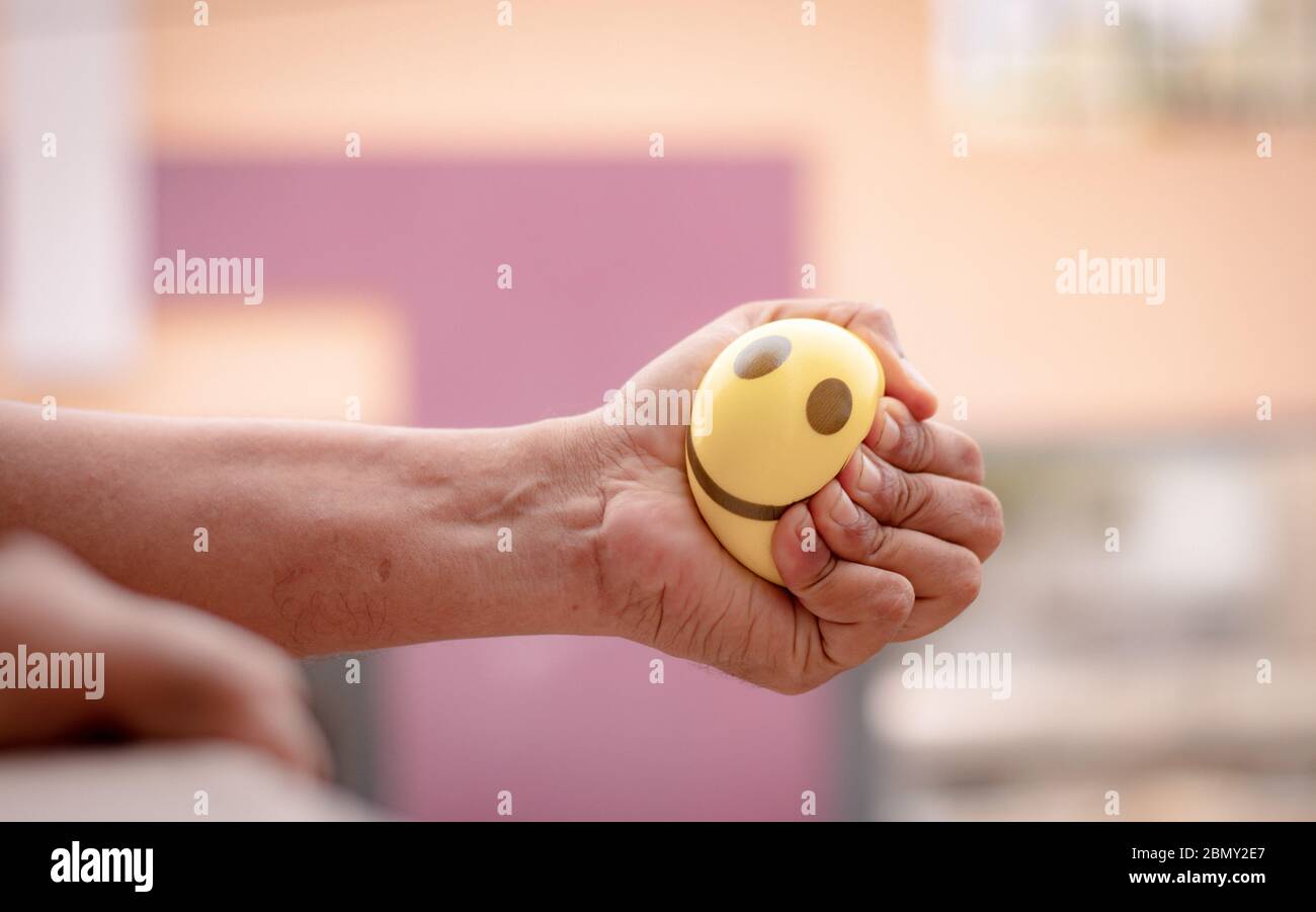 Hands squeezing or pressing stress ball at home to release stress - concept of stress buster Stock Photo