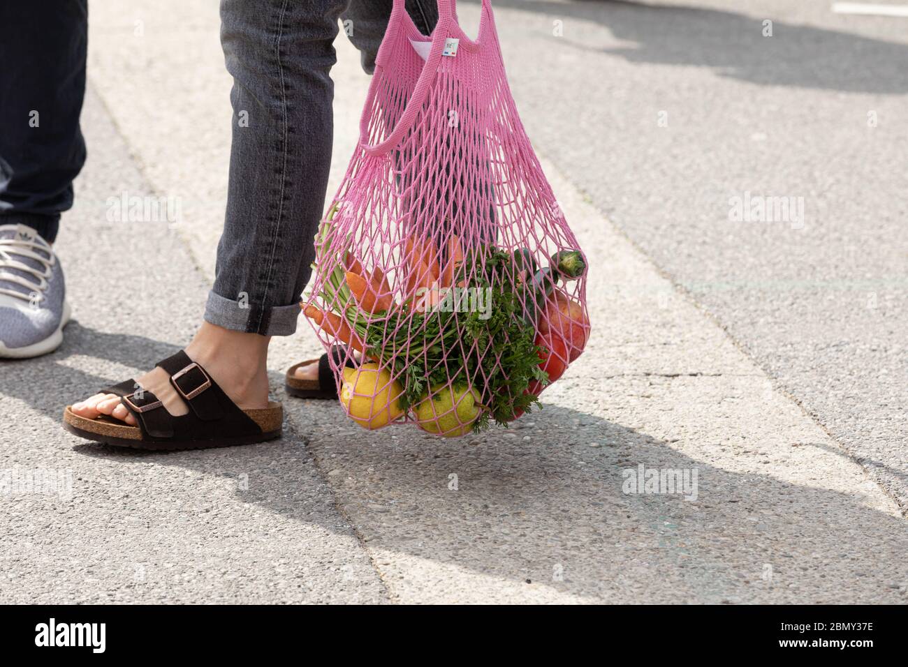 a women is carrying her fruit and vegetables. purchases in a mesh bag Stock Photo