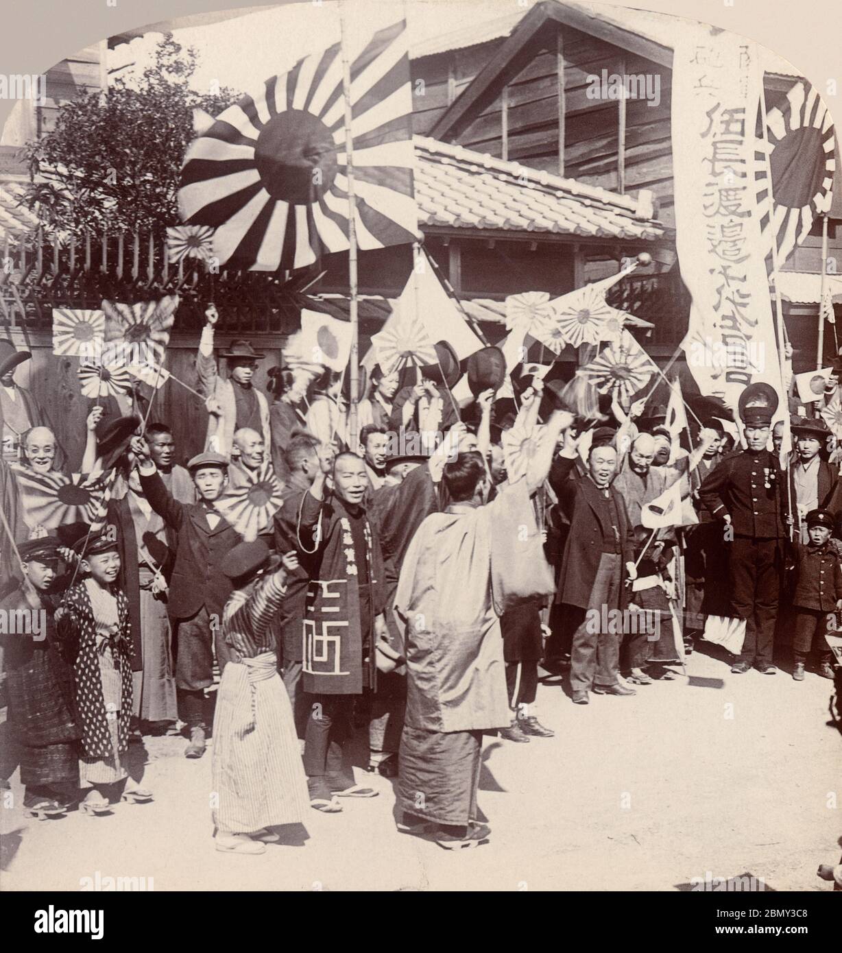 [ 1900s Japan - Russo-Japanese War ] —   Family and friends saying farewell to a young man going to war during the Russo-Japanese War (1904-1905), 1904 (Meiji 37).  They are waving rising sun flags (旭日旗, Kyokujitsu-ki). The flag is still used as Japan's naval ensign (軍艦旗, Gunkanki). Stock Photo