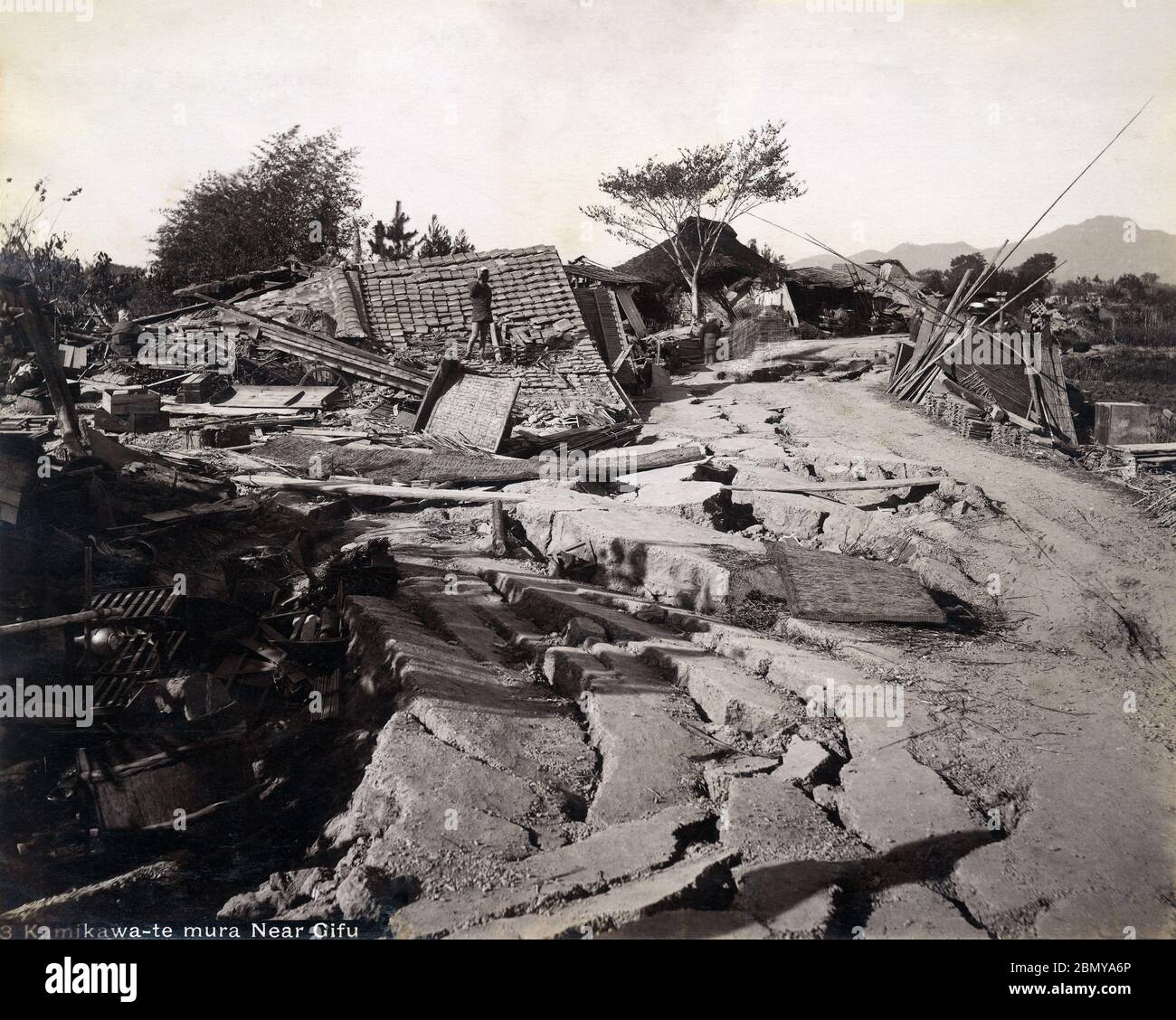 [ 1890s Japan - Nobi Earthquake ] —   A road with homes devastated by the Nobi Earthquake (濃尾地震, Nobi Jishin) of October 28, 1891 (Meiji 24).  The Nobi Earthquake measured between 8.0 and 8.4 on the scale of Richter and caused 7,273 deaths, 17,175 casualties and the destruction of 142,177 homes.  The caption identifies the location as Kamikawate-mura (上川手村) near Gifu. This area is now part of Gifu City).  19th century vintage albumen photograph. Stock Photo