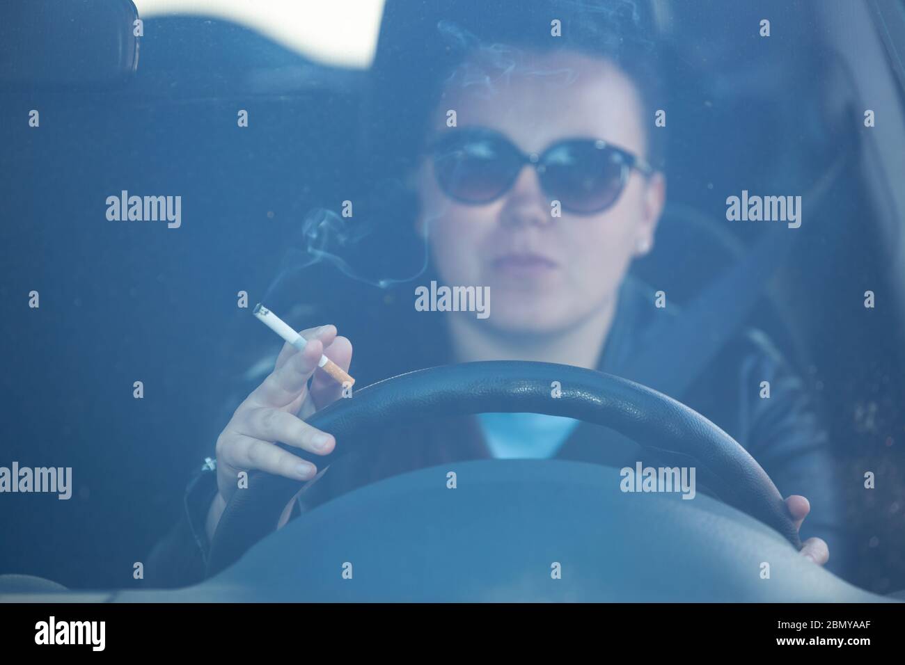 Close up of woman hand smoking cigarette inside the car while driving a