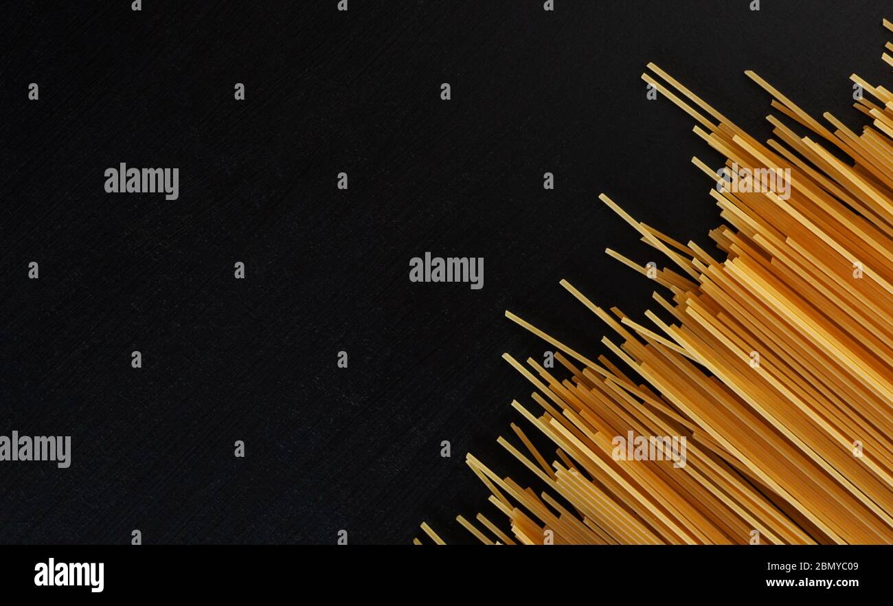 yellow raw homemade spaghetti paste on a black concrete background in ...