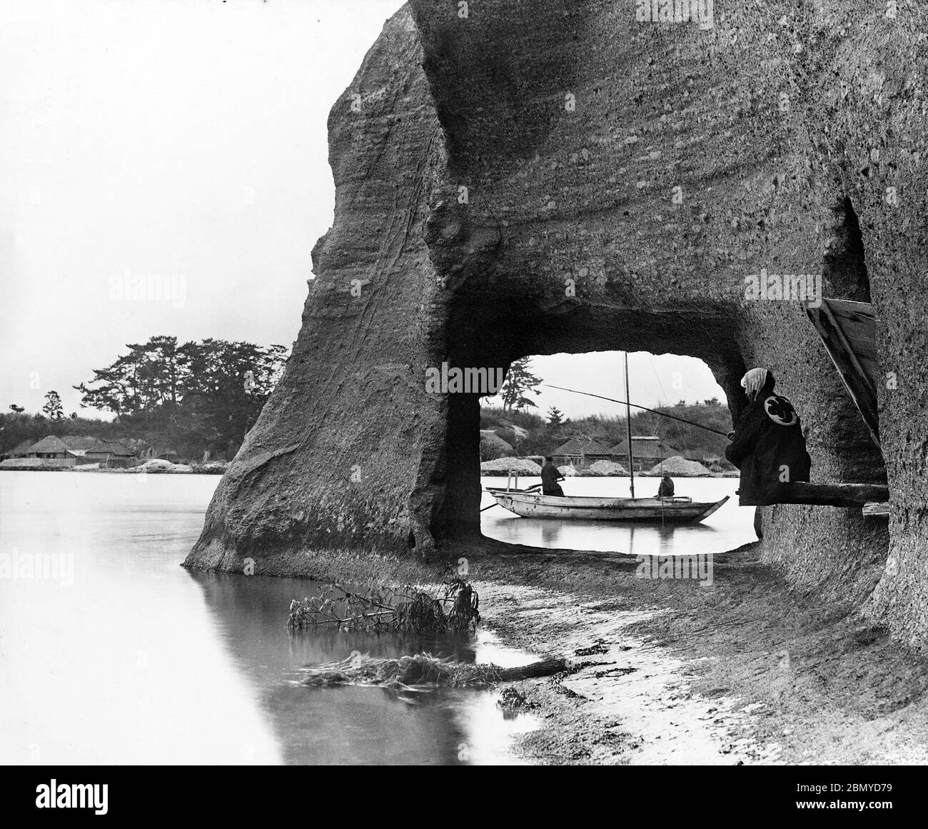 [ 1890s Japan - Japanese Fishermen in Matsushima ] —   Japanese fishermen near a cave in Matsushima, Miyagi Prefecture. The 260 tiny islands covered in pines are listed as one of the Three Views of Japan (日本三景, Nihon Sankei), a canonical list of Japan's three most celebrated scenic sights.  From a series of glass slides published (but not photographed) by Scottish photographer George Washington Wilson (1823–1893). Wilson’s firm was one of the largest publishers of photographic prints in the world.  19th century vintage glass slide. Stock Photo