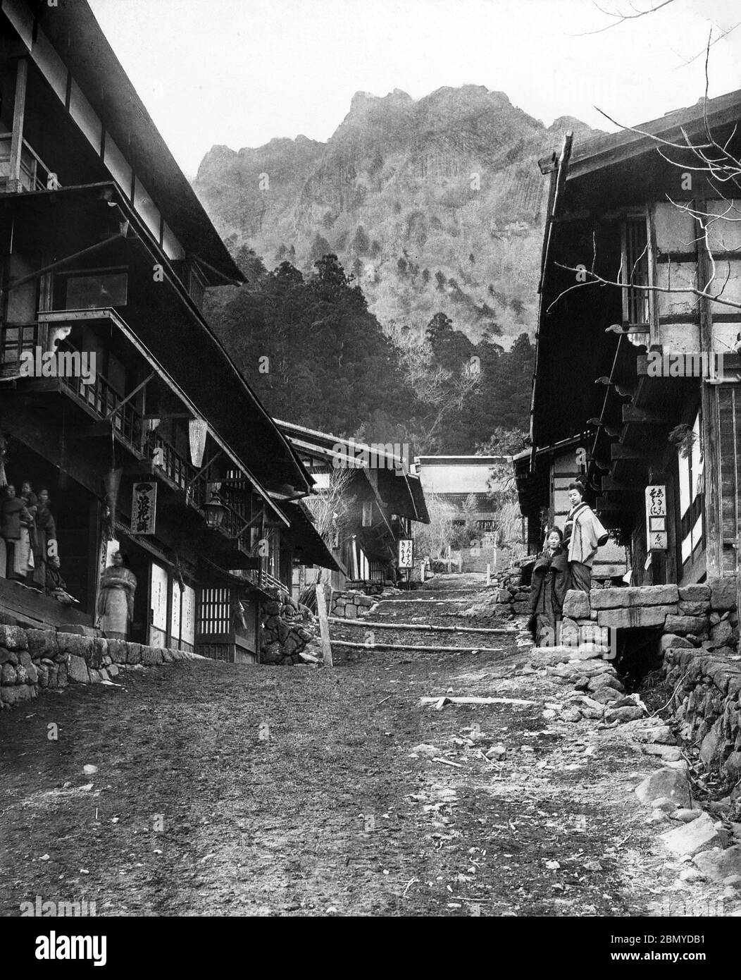[ 1890s Japan - Japanese Mountain Town ] —   A rare view of Japanese inns along the road to Myogi Shrine (妙義神社) in Tomioka (富岡市), Gunma Prefecture. In the background Mount Myogi (妙義山) can be seen. The area was near the Nakasendo, one of the two routes that connected Edo (modern-day Tokyo) to Kyoto.  Mt. Myogi is one of the Three Great Places of Rugged Beauty in Japan (日本三大奇勝, Nihon Sandai Kisho). The other two are Yabakei Gorge (耶馬溪) in Kyushu and Kankakei Gorge (寒霞渓) in Shikoku.  From a series of glass slides published (but not photographed) by Scottish photographer George Washington Wilson ( Stock Photo