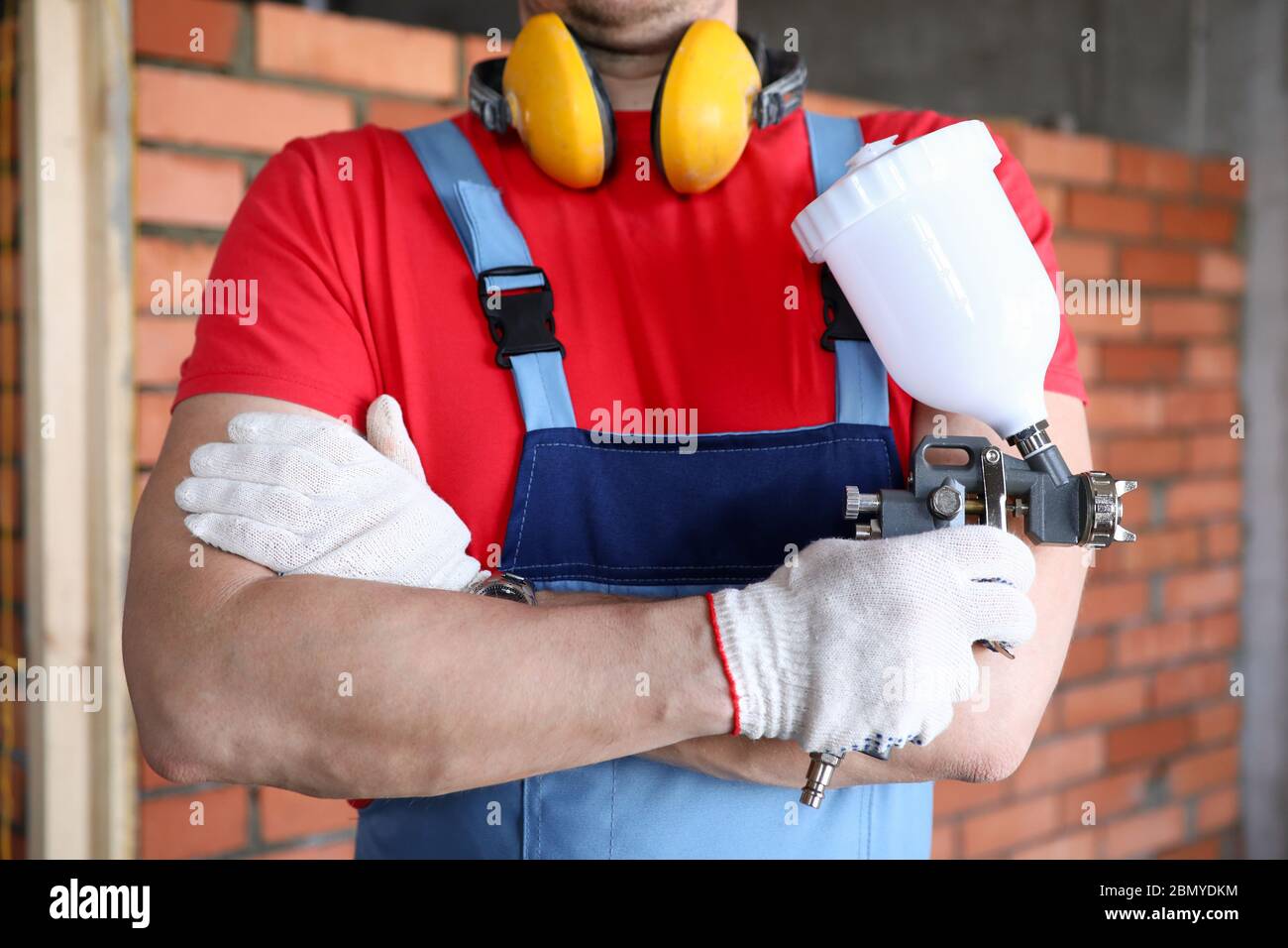 Close-up builder holding spray gun in his hands Stock Photo