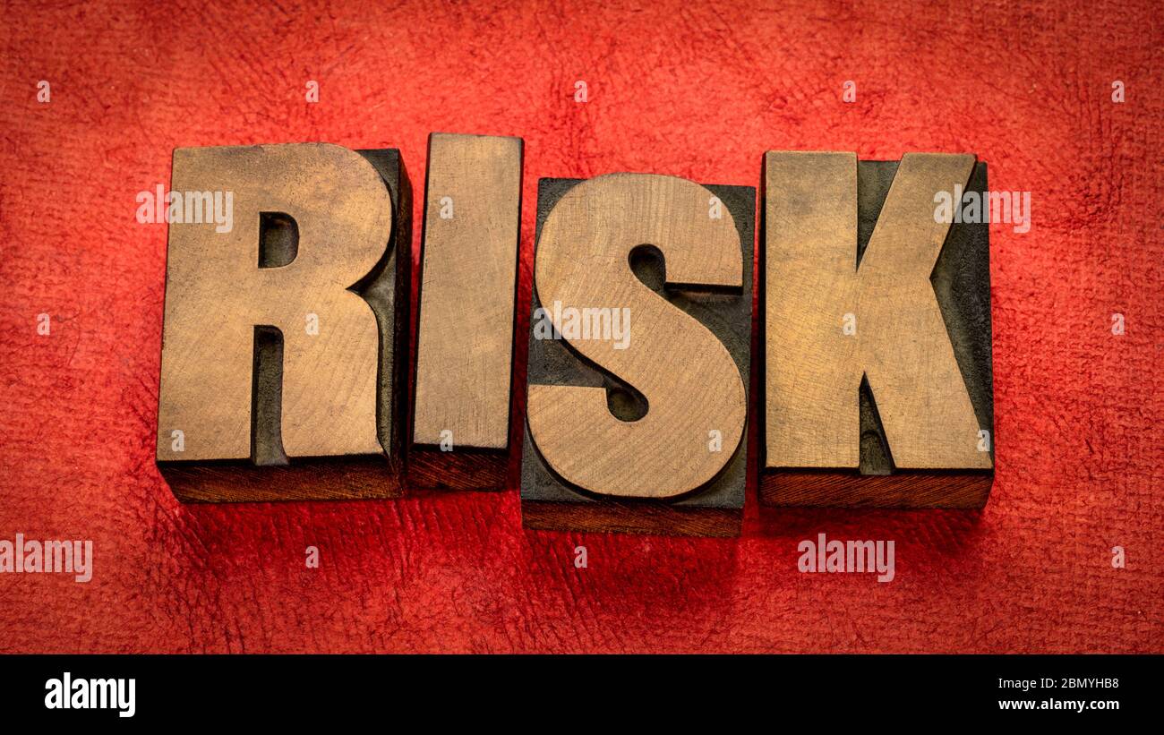 risk word abstract in vintage letterpress wood type against red textured paper, business, danger and uncertainty concept Stock Photo