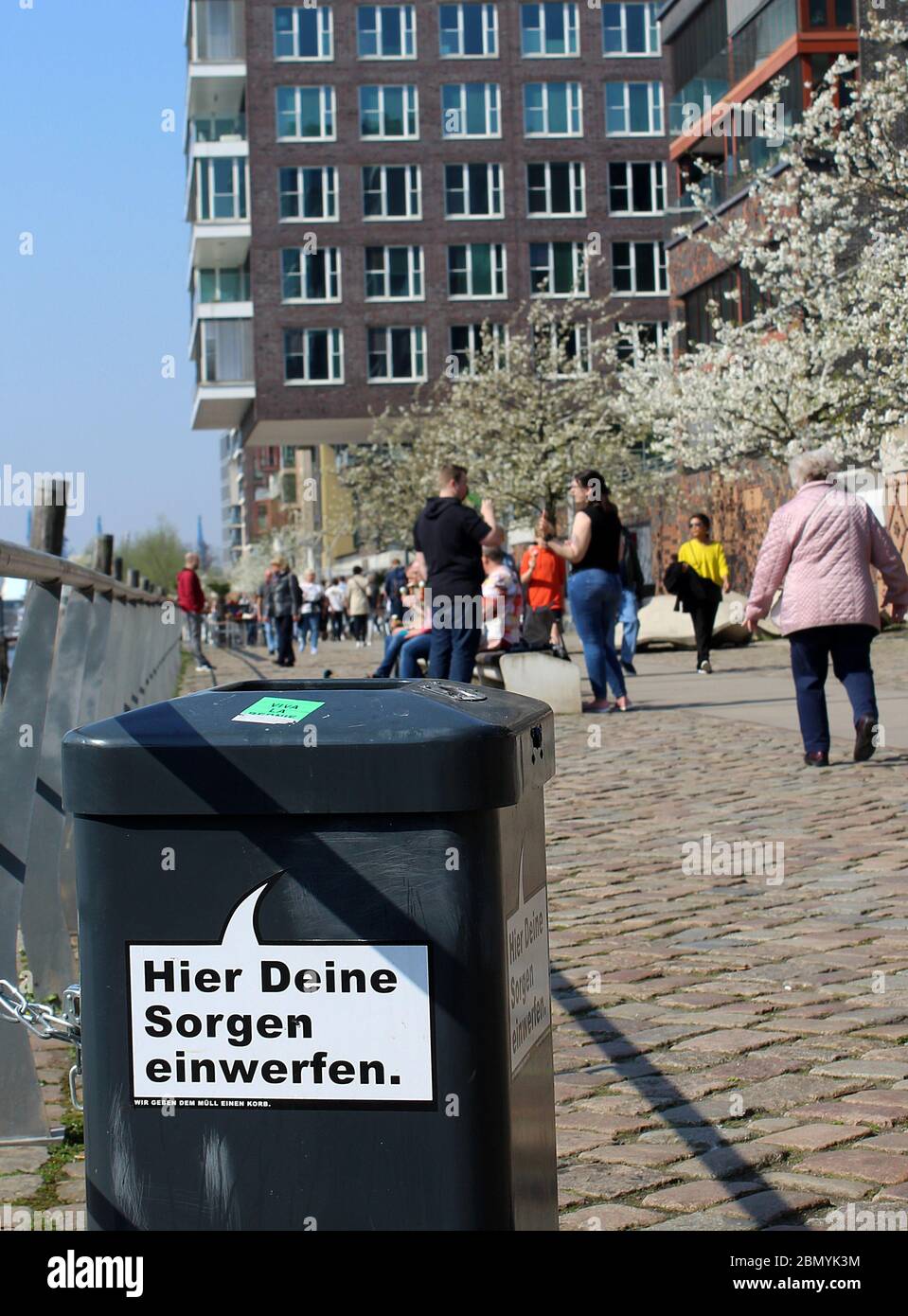 'Drop your worries here. We give trash the brushoff.' Trash can with uplifting German saying in speech bubble. Mental health concept, environment Stock Photo