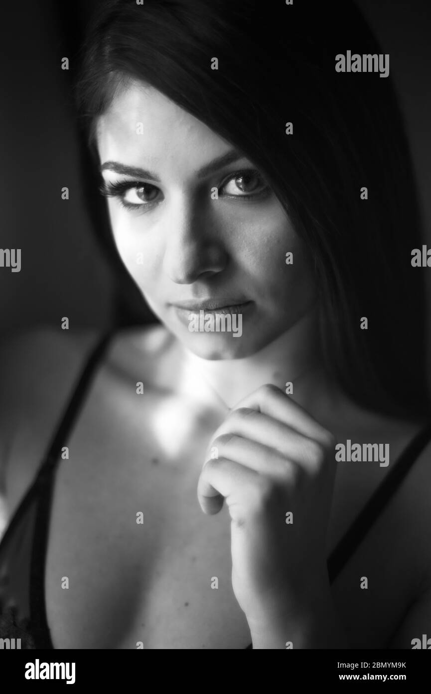 A black and white image of a young caucasian woman wearing lingerie at a boudoir location. Stock Photo