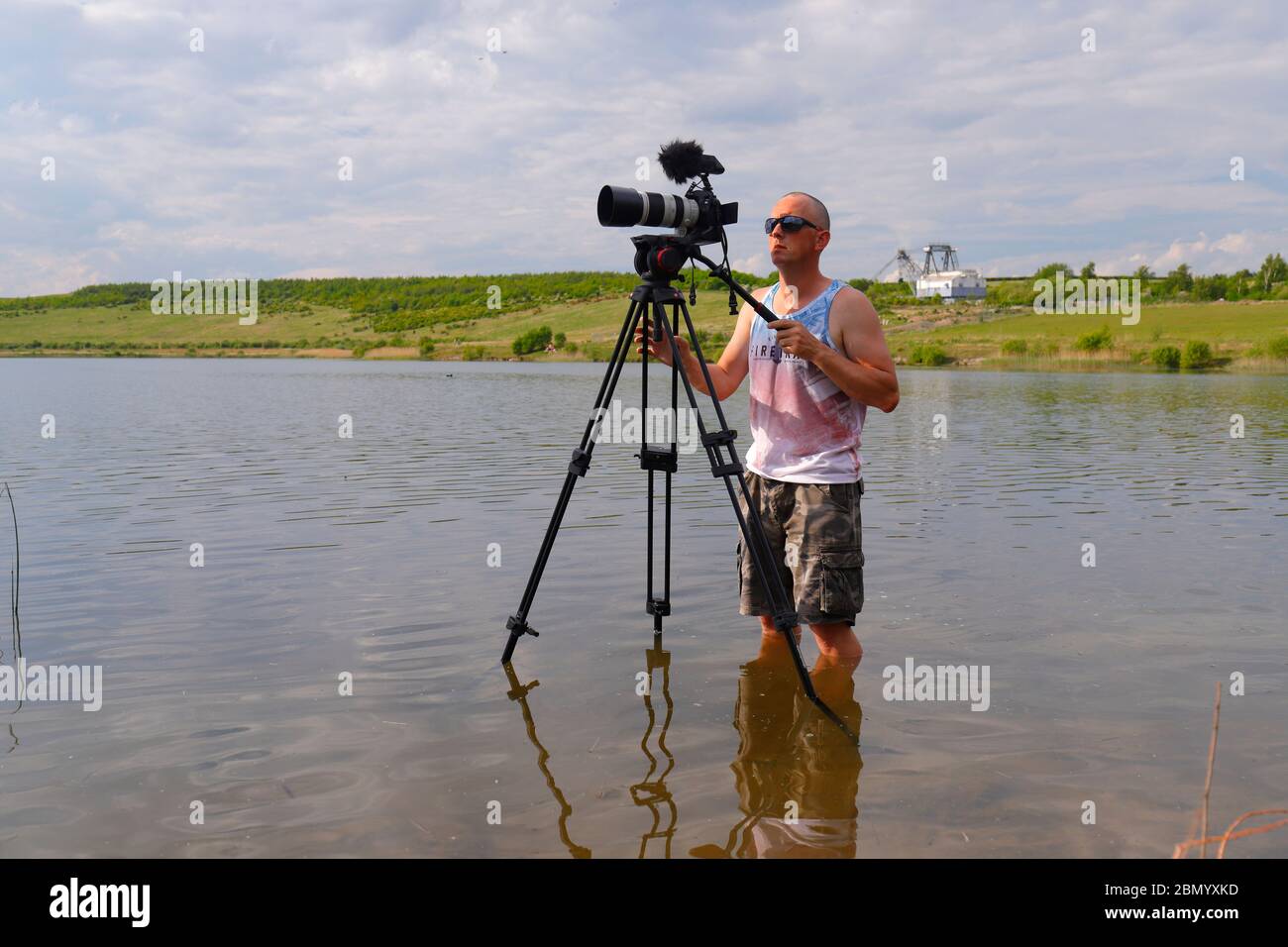 A photographer standing in shallow water, to get the angle that wasn't possible from the edge of the lake at RSPB St Aidan's Stock Photo