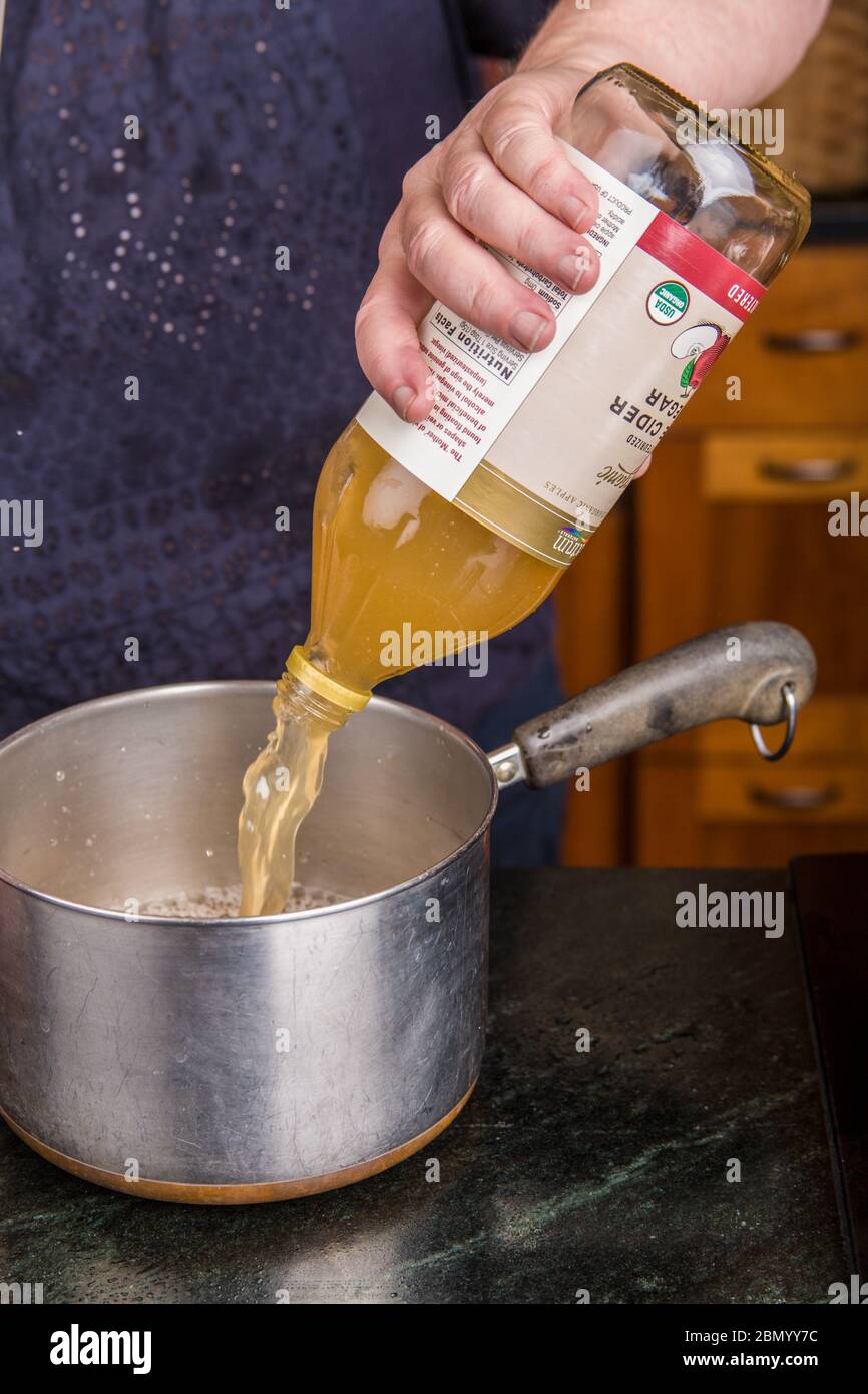 Woman pouring Spectrum unpasturized (aka raw) apple cider vinegar into a pan as part of the pickling solution for canning pickled beets. Stock Photo
