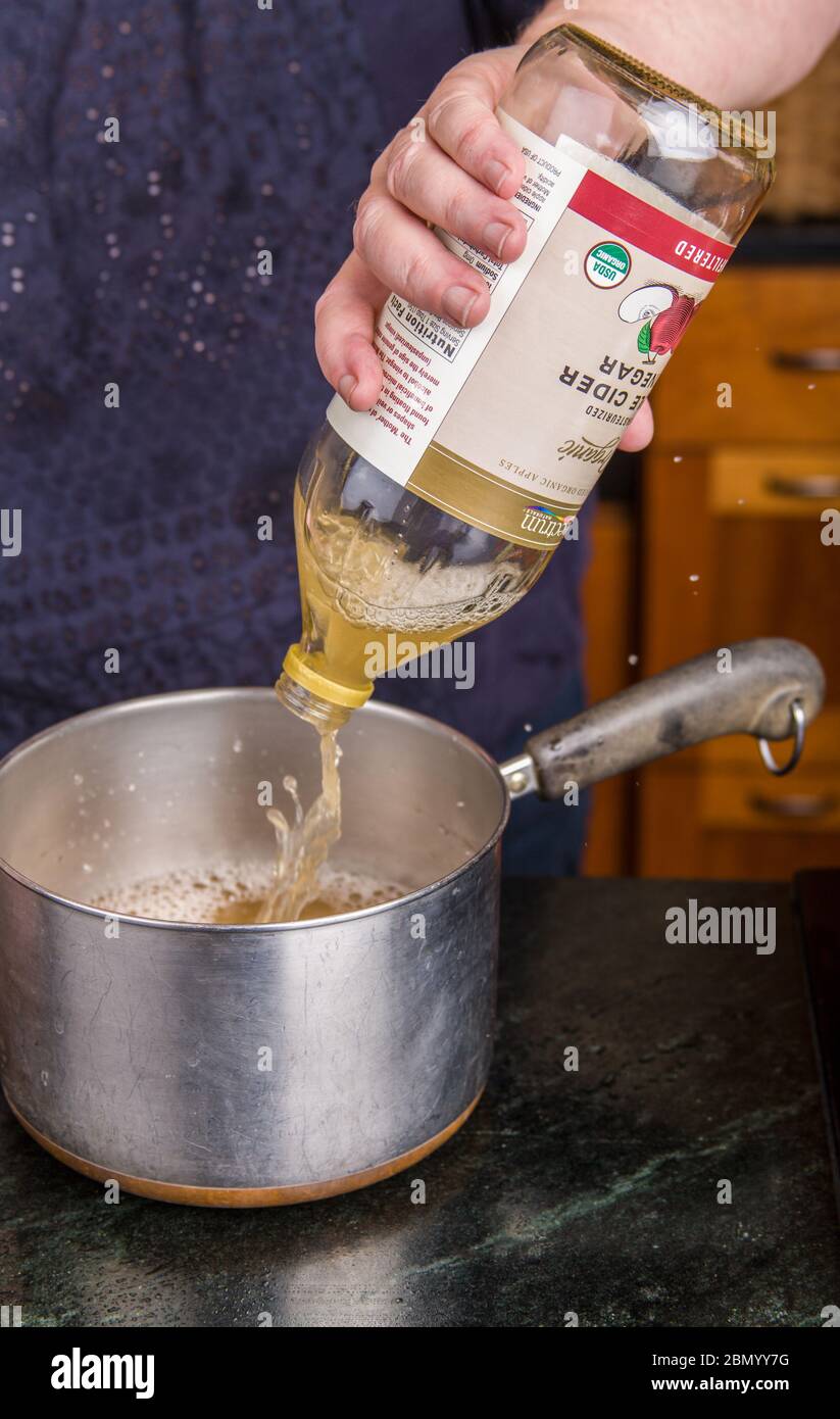 Woman pouring Spectrum unpasturized (aka raw) apple cider vinegar into a pan as part of the pickling solution for canning pickled beets. Stock Photo