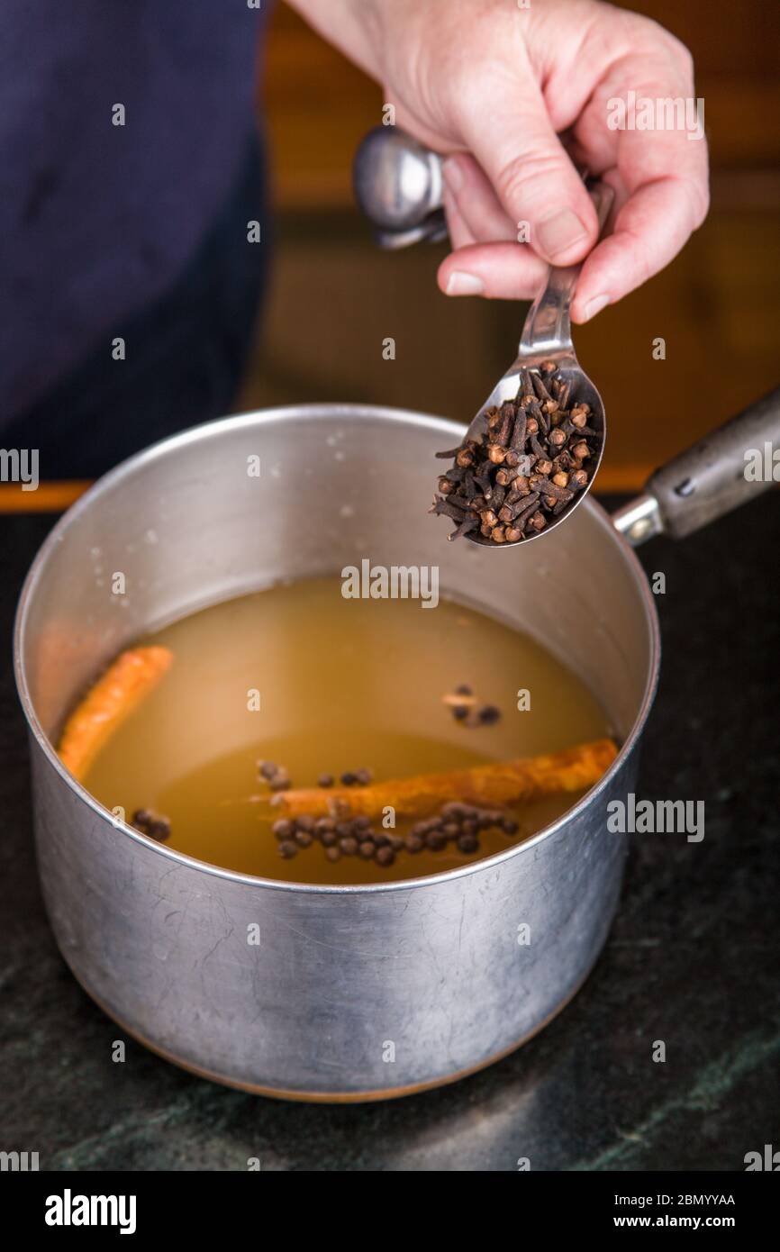 Woman pouring whole cloves into a pickling solution which will be used to make home-canned pickled beets Stock Photo