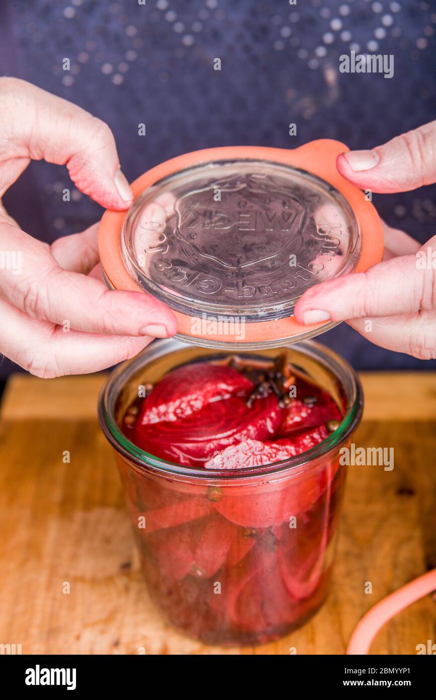 Woman placing a lid on a Weck canning jar of beets and pickling