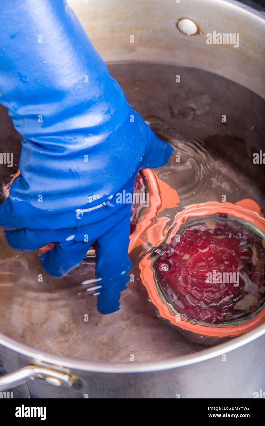 Woman placing a Weck canning jar of beets in pickling solution into a