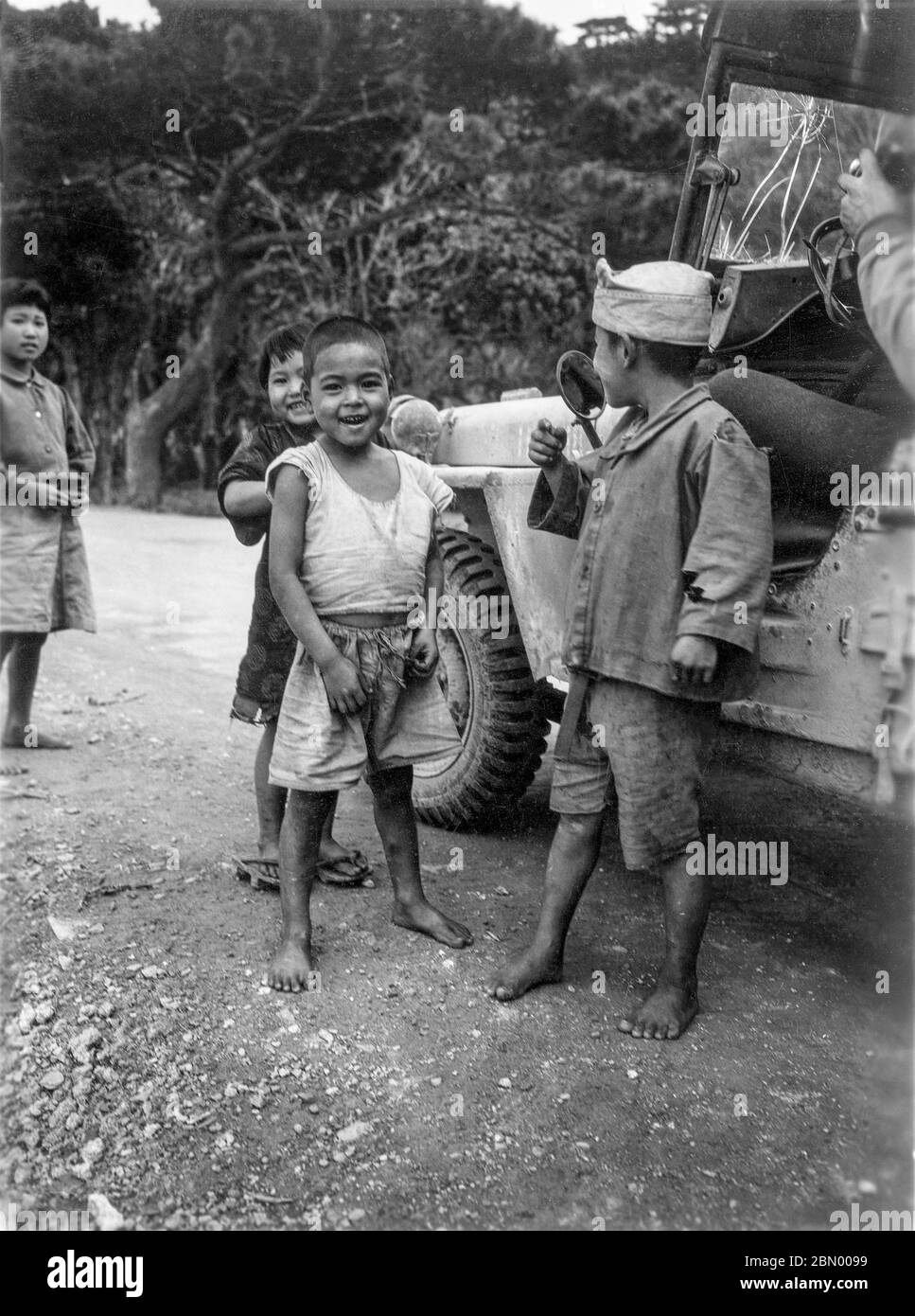 [ 1946 Japan - Okinawan Children ] —   Okinawan children begging for candy next to a US military Jeep, 1946 (Showa 21).  20th century gelatin silver print. Stock Photo