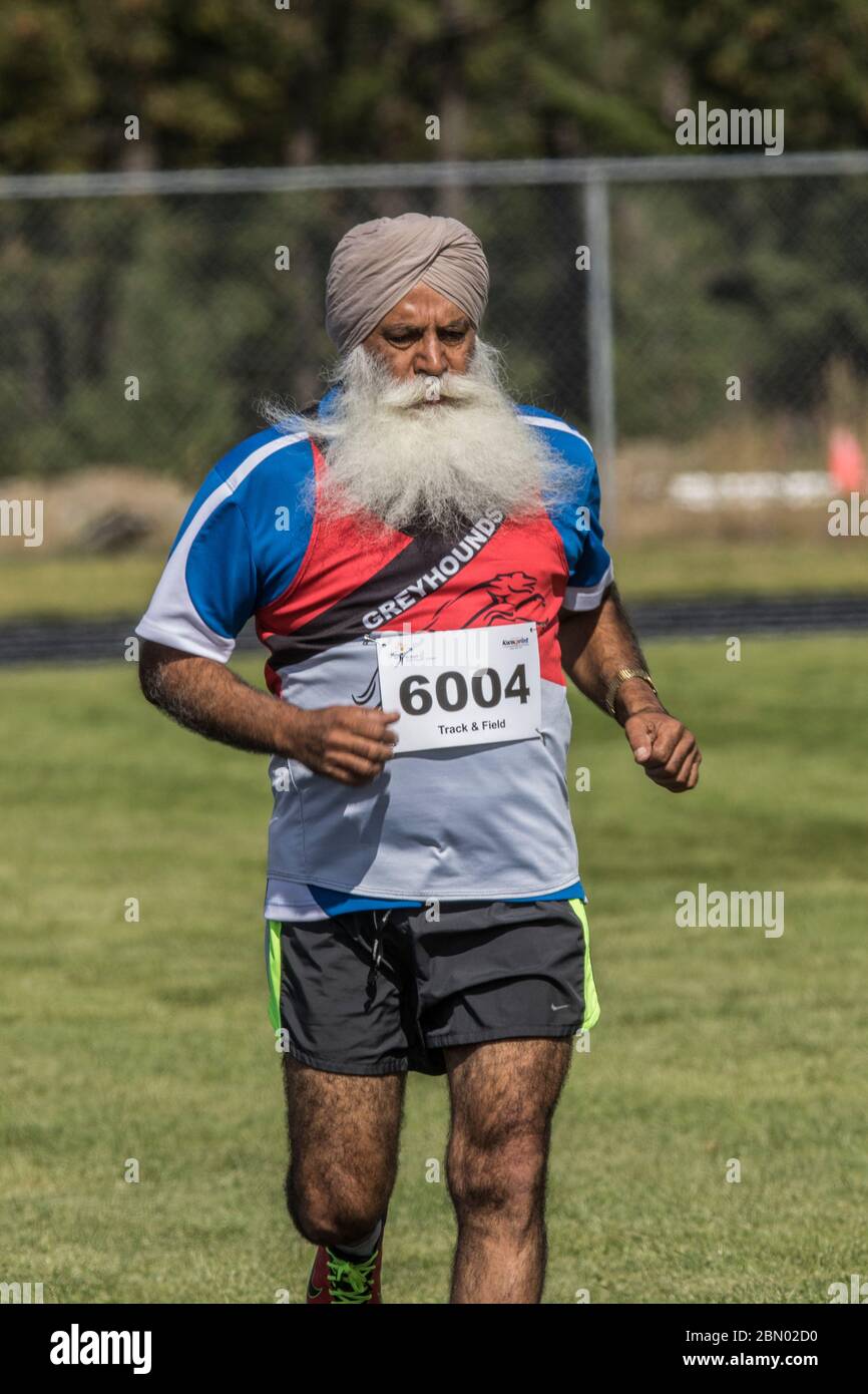Senior Males( 60 to 70 ) competing in 200 M  race. East Indian runner with big white beard. Stock Photo