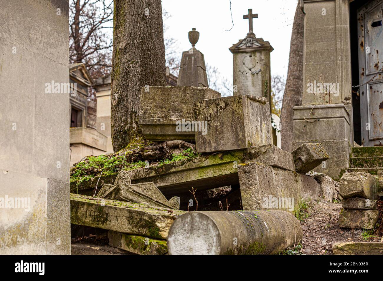 Gravestones cracked apart by tree roots and left to decay, overgrown with moss, at the Père-Lachaise Cemetery in Paris. Taken on 18 February 2012. Stock Photo