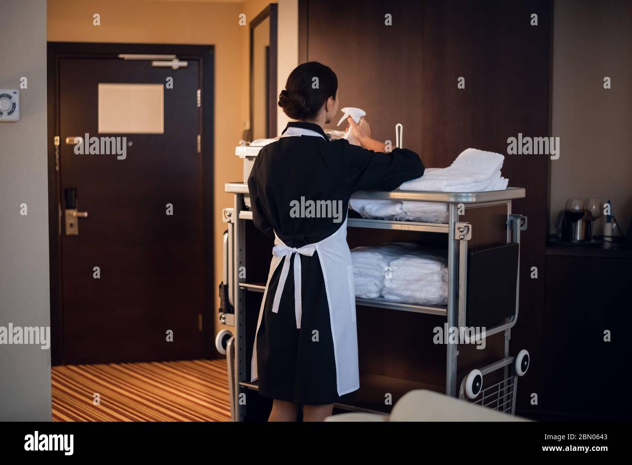 Hotel maid working with cleaning cart and cleaning supplies Stock Photo