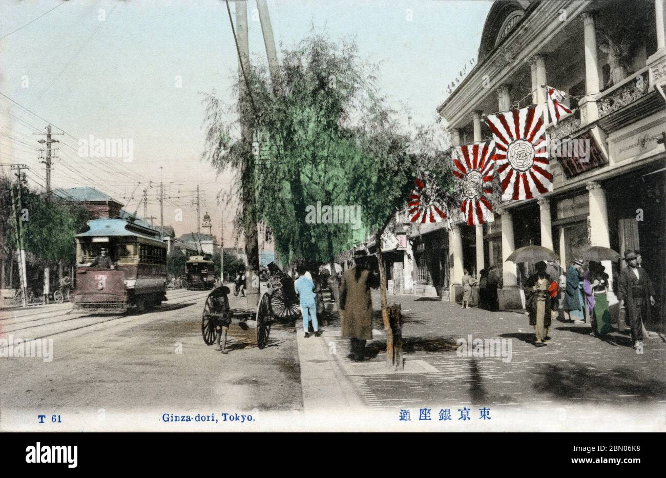 [ 1900s Japan - Ginza Street View, Tokyo ] —   Streetcars and pedestrians on Ginza in Tokyo, ca. 1907 (Meiji 40).  The building on the right, with the rising sun flags (旭日旗, Kyokujitsu-ki), is Tenshodo (天賞堂).  In the far background, the landmark tower of the Hattori Building (服部時計店ビル) can be seen.  20th century vintage postcard. Stock Photo