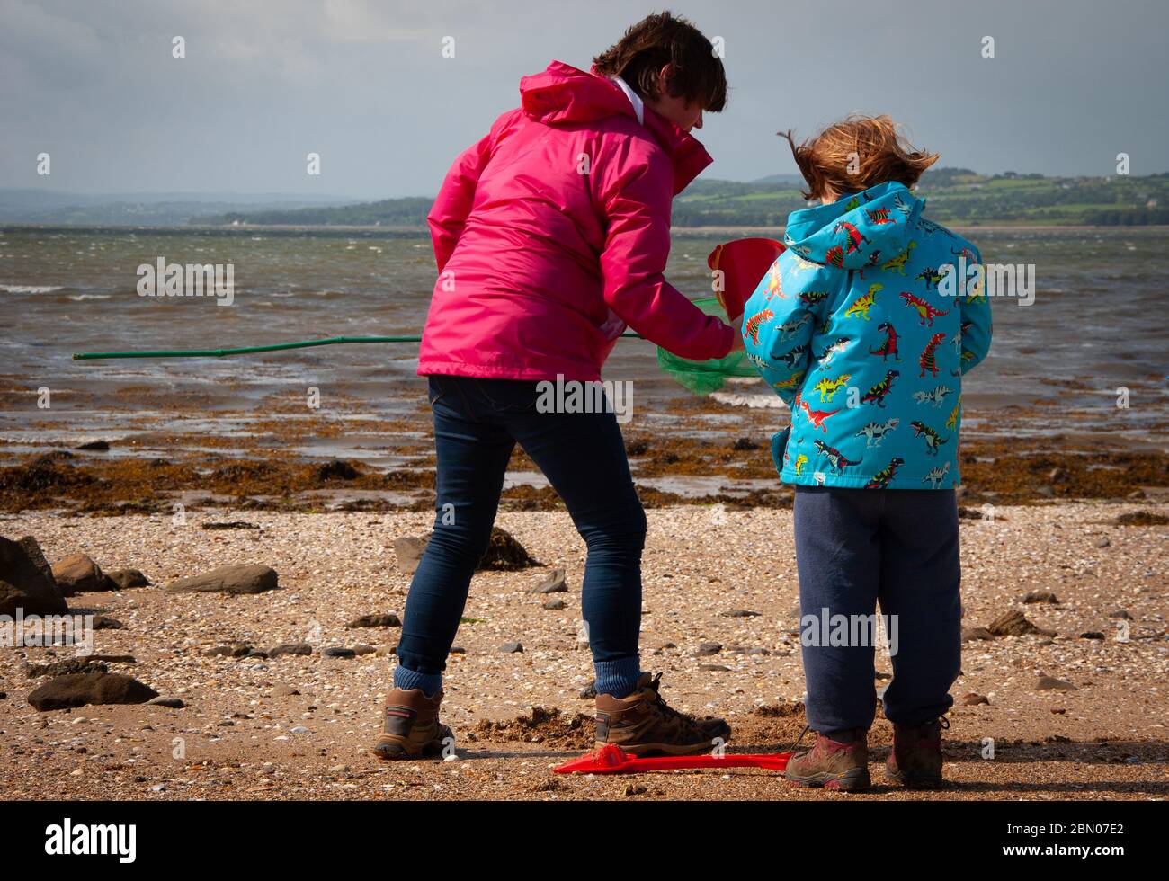 Mother and daughter in bright coats on an Irish beach with bucket and