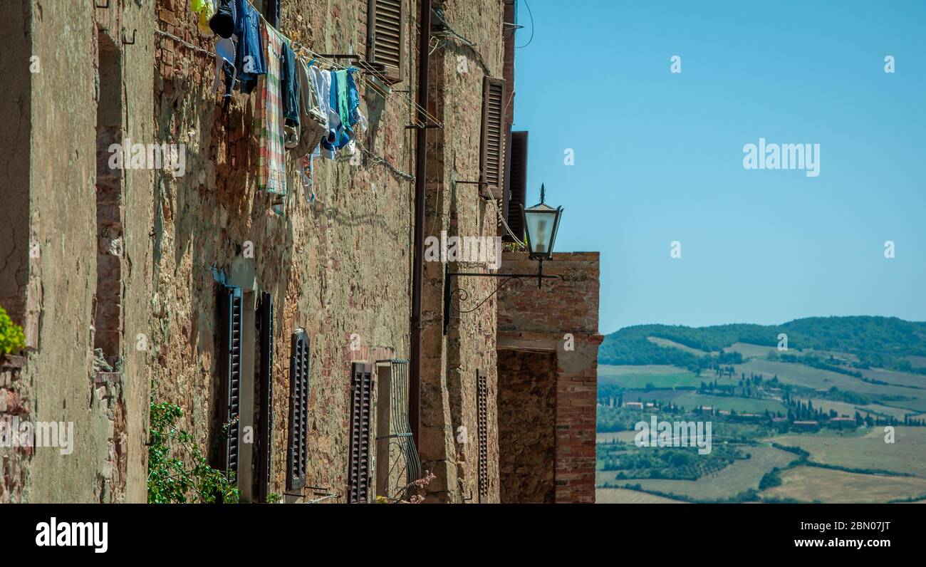 Clothes hang out on the side of an old rustic medieval house apartment in Montepulciano, Tuscany, Italy with fields and blue sky in background Stock Photo