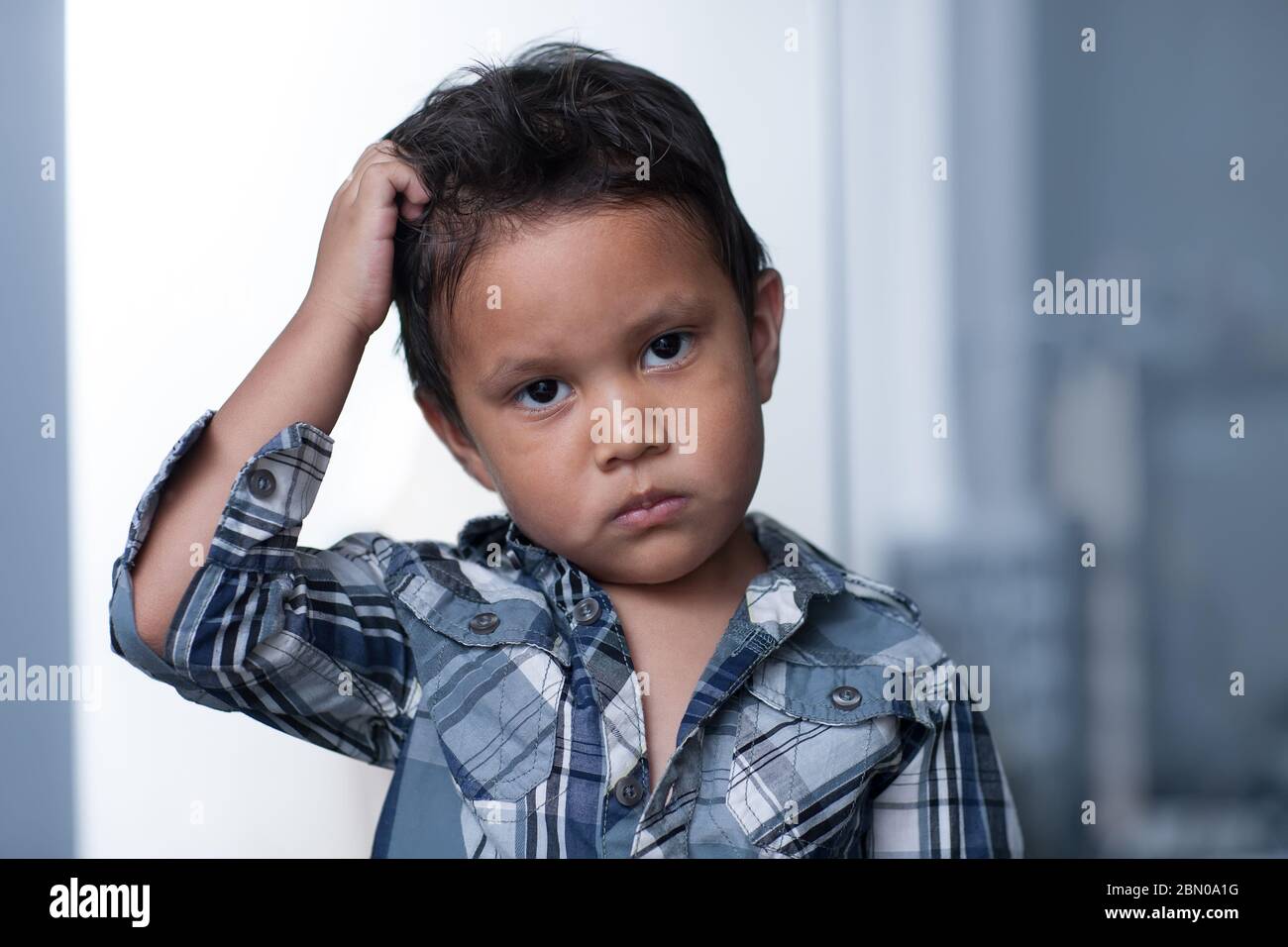 A child exibiting a mood disorder or depressed irritability, expressing sadness and pulling of his hair. Stock Photo