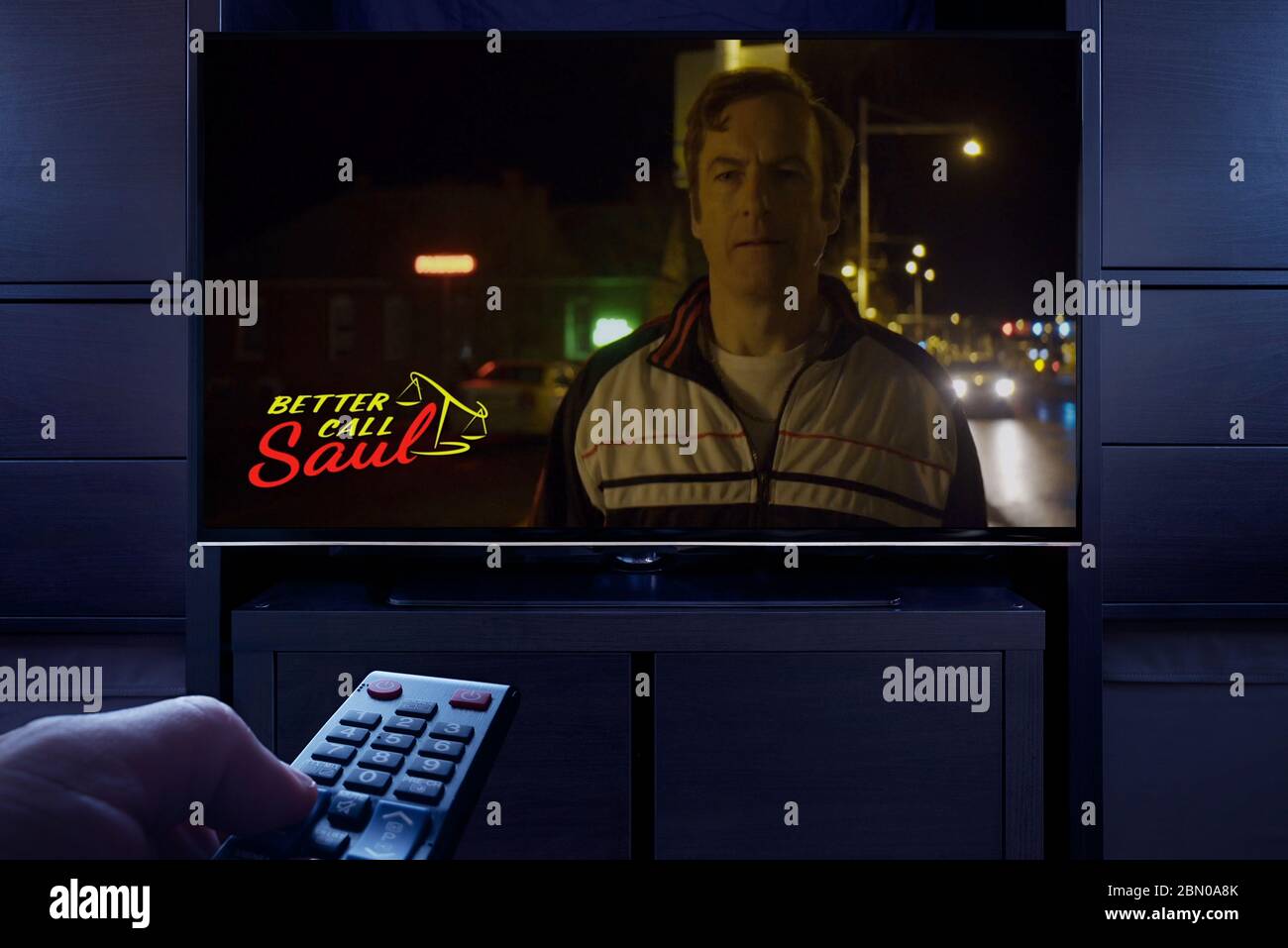 A man points a TV remote at the television which displays the Better Call Saul main title screen (Editorial use only). Stock Photo