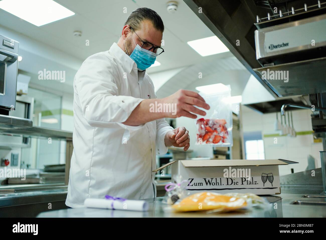 Deidesheim, Germany. 09th May, 2020. Stefan Neugebauer, head chef, fills a carton with food in the kitchen of the restaurant and hotel 'Deidesheimer Hof'. (to dpa 'Partition walls and flutter band - restaurants and pubs in starting blocks') Credit: Uwe Anspach/dpa/Alamy Live News Stock Photo