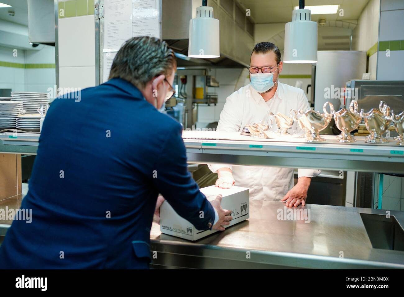 Deidesheim, Germany. 09th May, 2020. Stefan Neugebauer (r), head chef, hands out a carton of ready-made food in the kitchen of the restaurant and hotel 'Deidesheimer Hof'. (to dpa 'Partition walls and flutter band - restaurants and pubs in starting blocks') Credit: Uwe Anspach/dpa/Alamy Live News Stock Photo