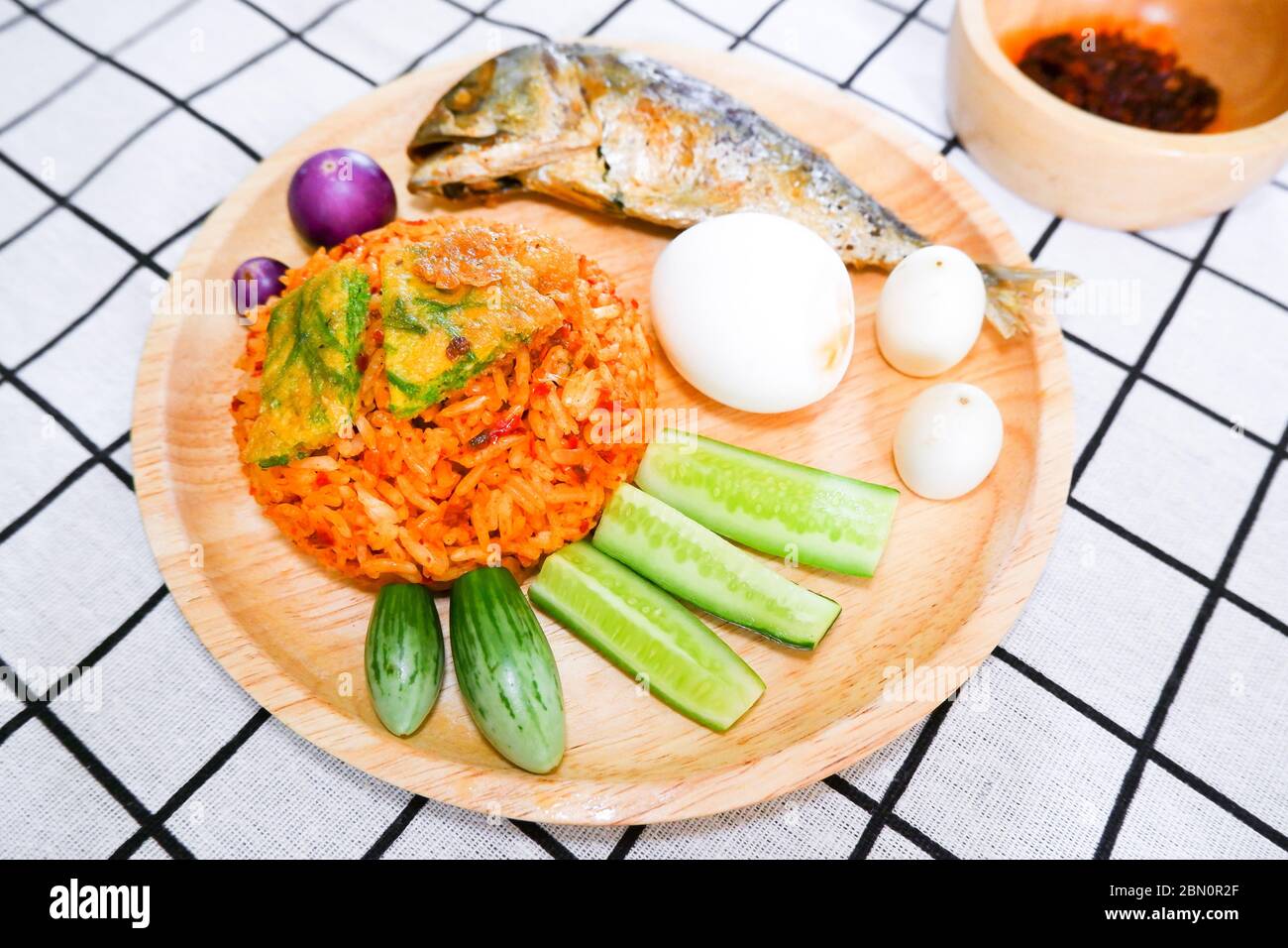 Fried rice with prik pao (Chilli paste with soya bean oil), omelet with cha om, boiled chicken egg, cucumber, eggplant and fried mackerel in wooden pl Stock Photo