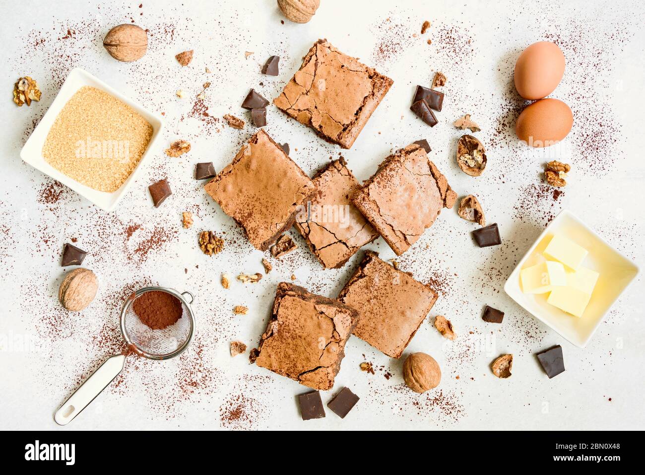 Top view of freshly baked home made brownie cake arranged with recipe ingredients over white rustic background. Stock Photo