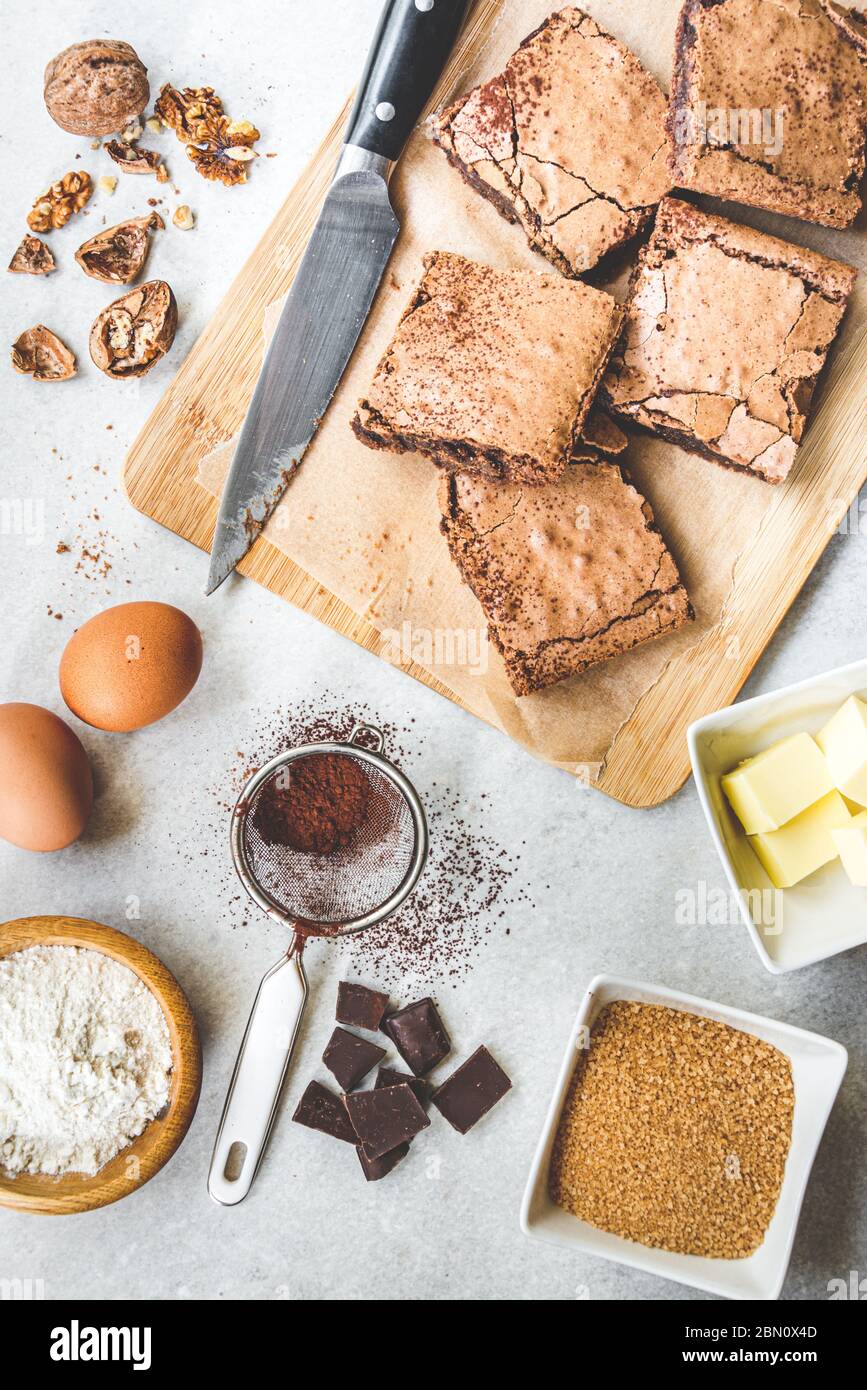 Top view of freshly baked home made brownie cake arranged with recipe ingredients over white rustic background. Stock Photo
