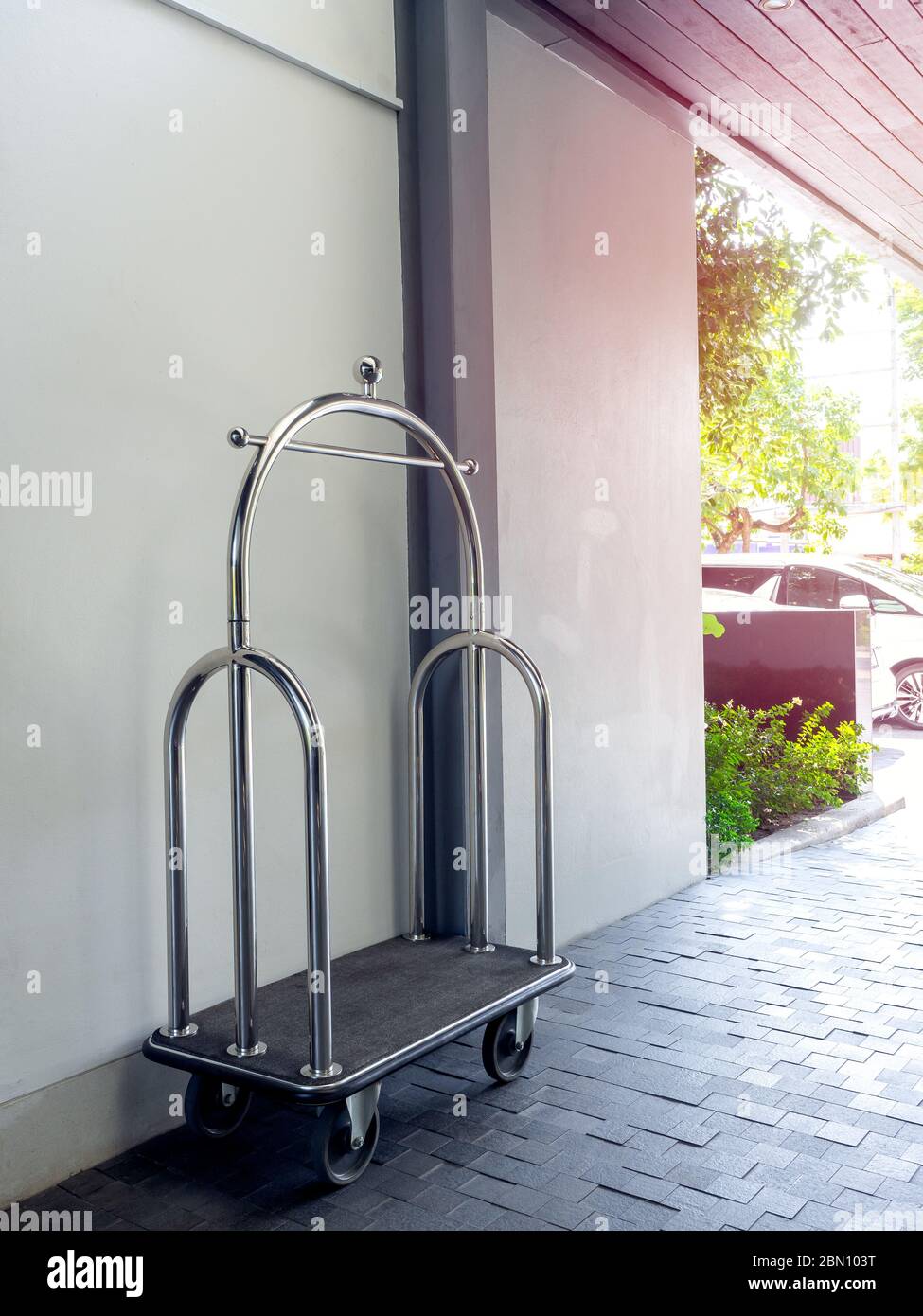 Empty silver chrome luxury hotel luggage trolley cart on a white wall