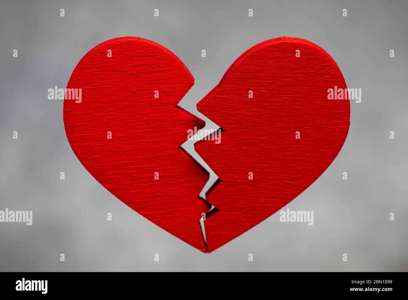 Broken heart. Crack in the red heart, Breaking the relationship. Grey background Stock Photo
