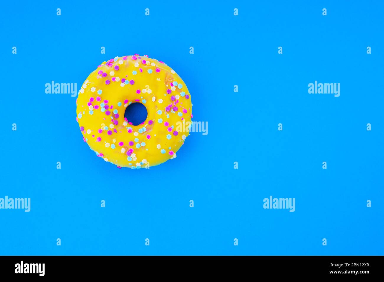 Yummy yellow donut isolated over blue background. Stock Photo