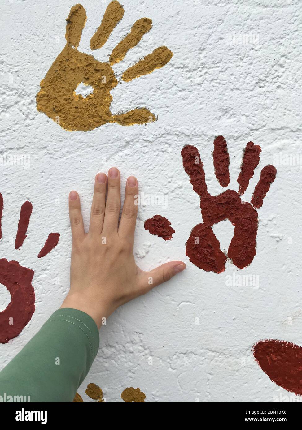 Handprints on a white wall. Drawing in bright ink, hand prints. Girl's hand near. No faces Stock Photo