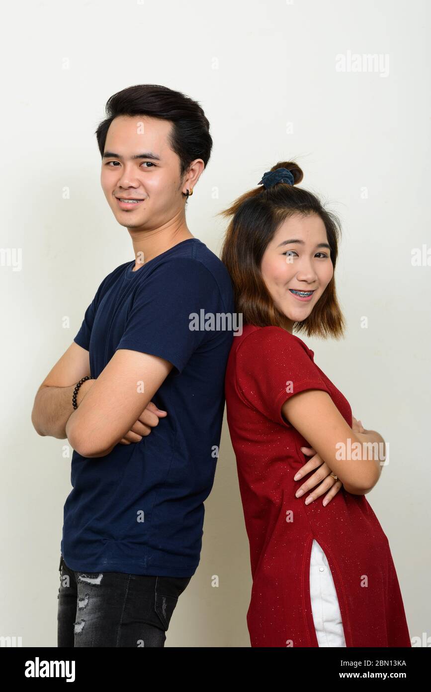 Portrait of happy young Asian couple leaning on each other with arms ...