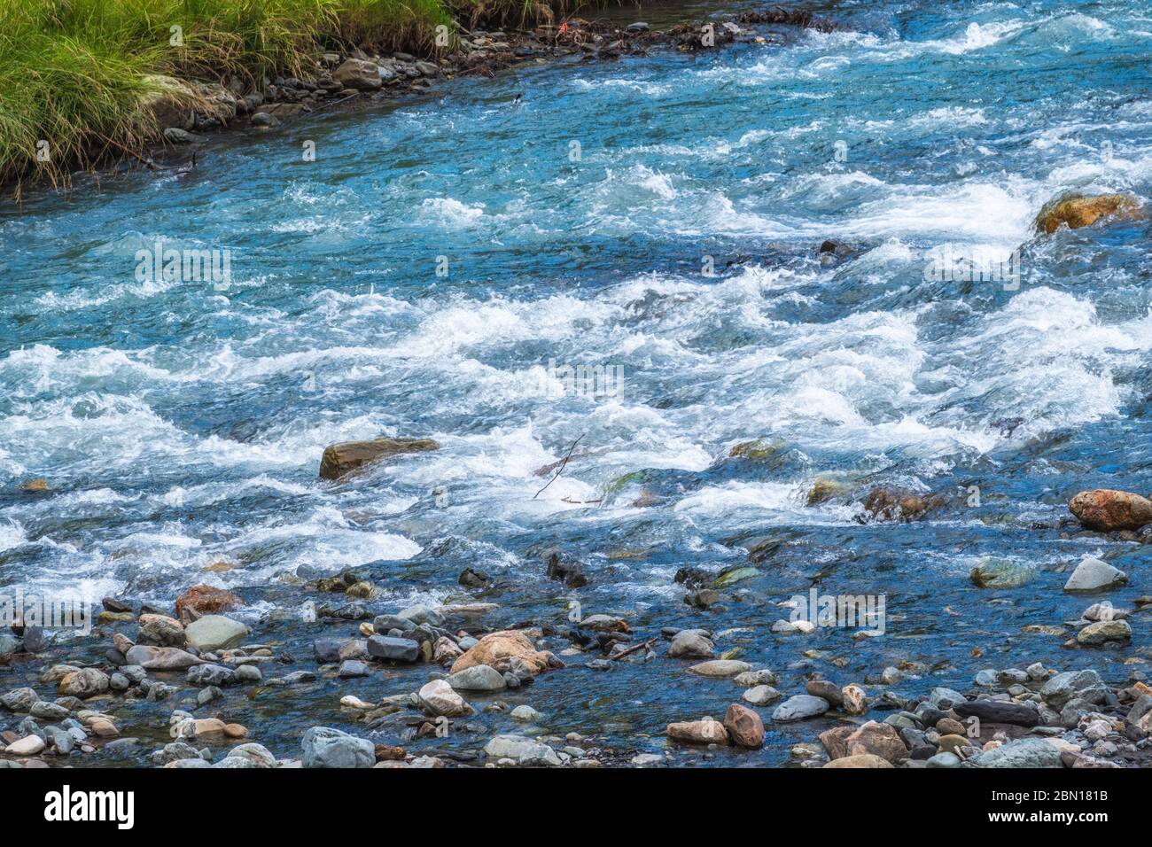Stones in water riffle of mountain river. Powerful water stream 