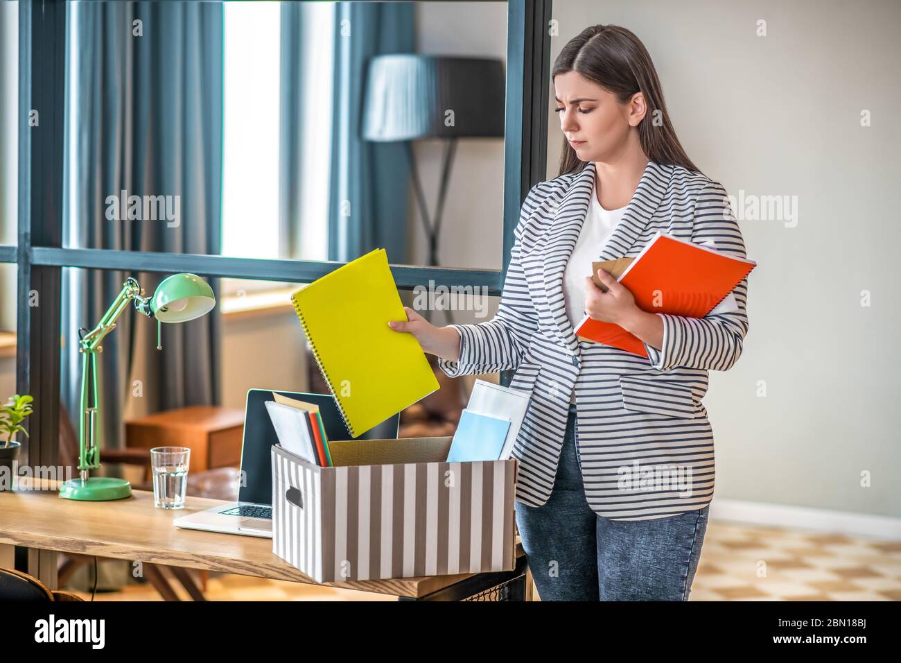 Young woman in a striped jacket standing with files in her hands Stock Photo