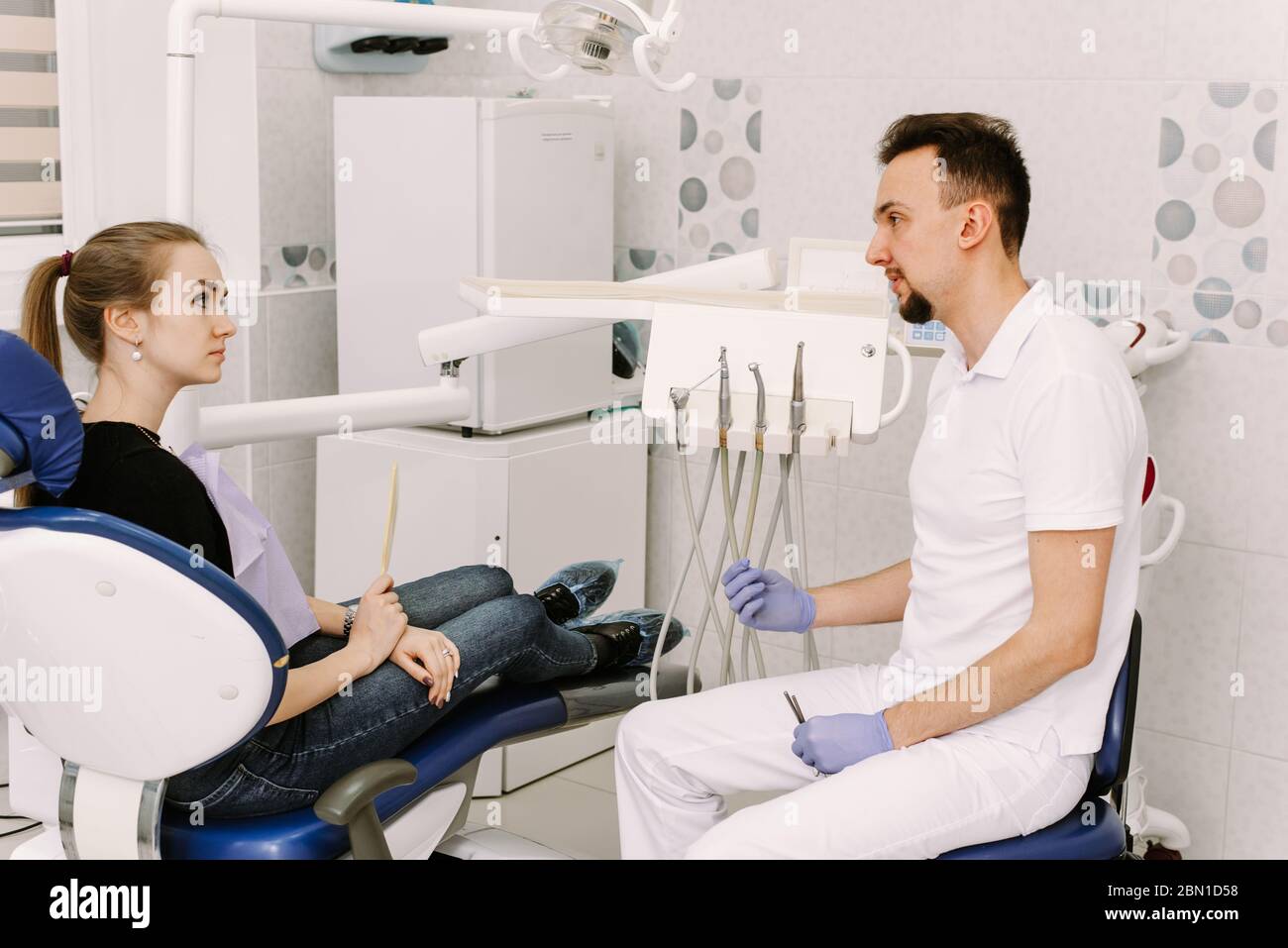 A beautiful girl sits in the dentist's chair and listens to the doctor. Dentist appointment and dental health care. Stock Photo