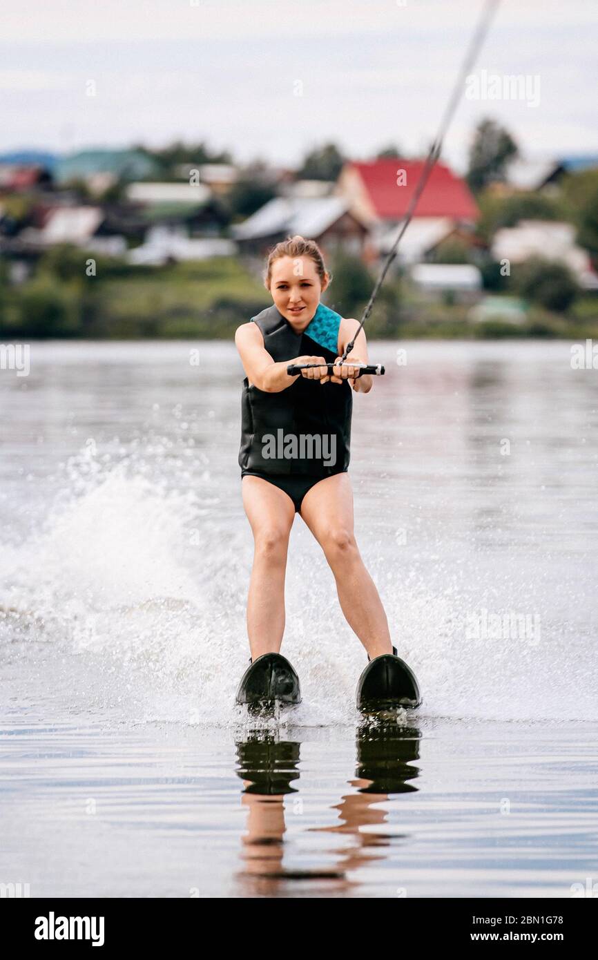 woman on water skiing on lake on background of village Stock Photo